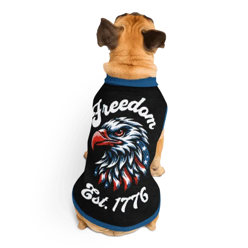 Dog wearing a black shirt with an eagle design and 'Freedom Est. 1776' text on a white background