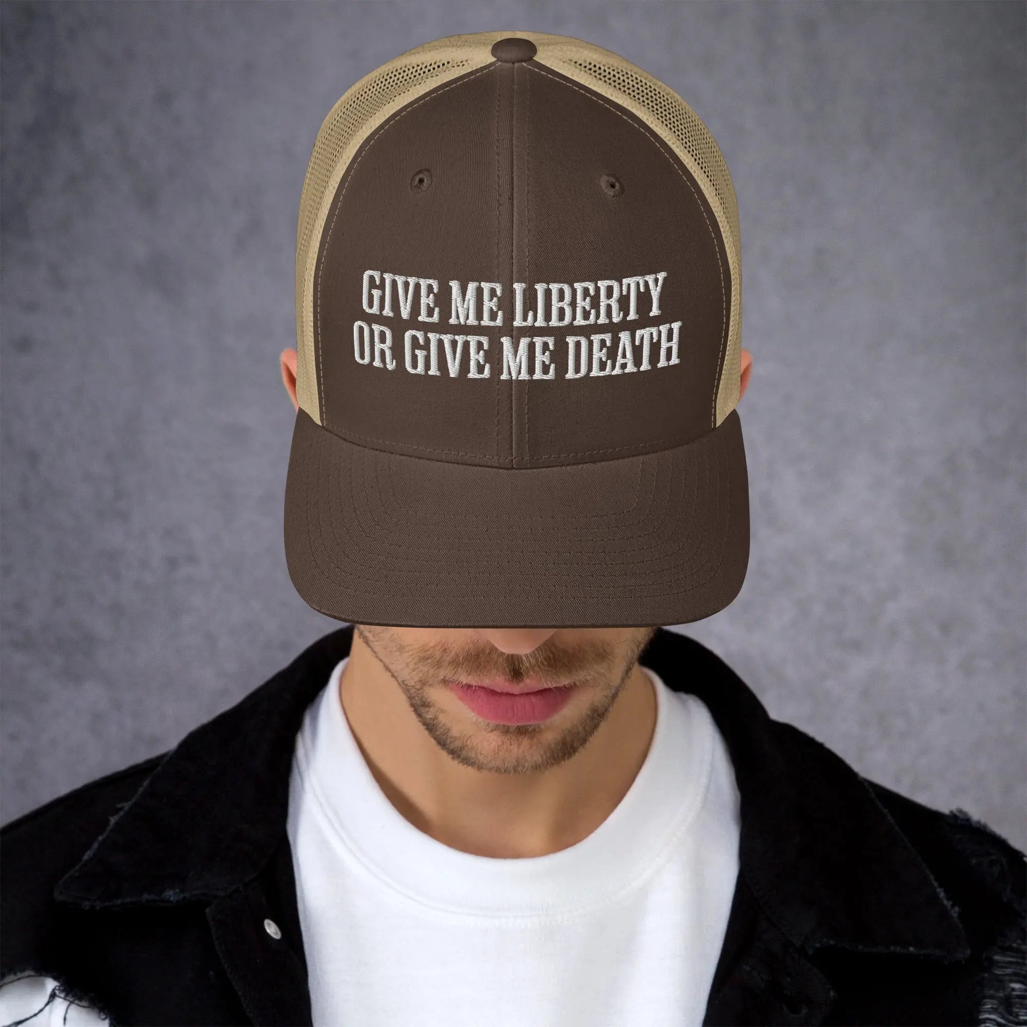 A man wearing a brown and khaki patriotic trucker hat with the text "Give Me Liberty Or Give Me Death."