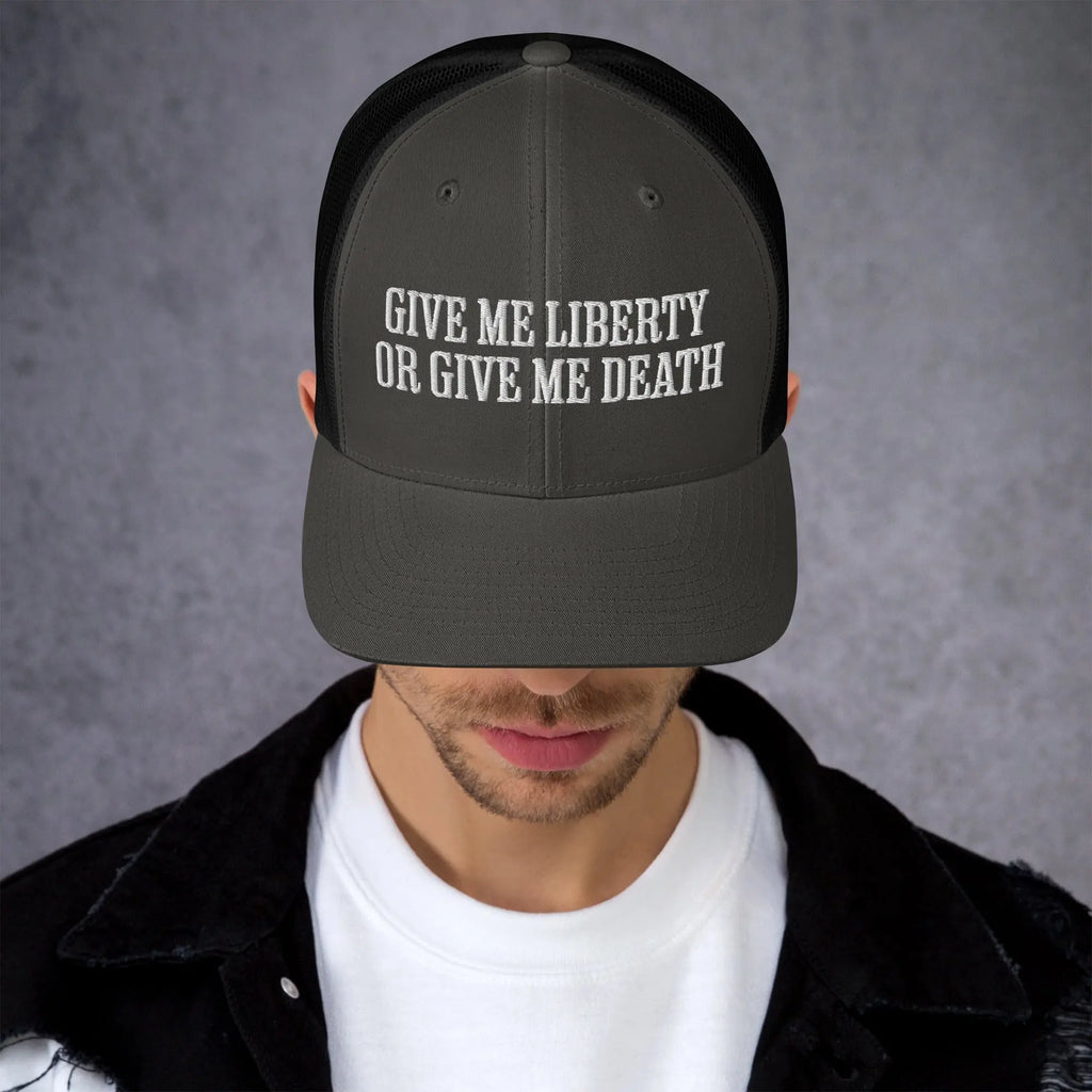 A man wearing a charcoal and black patriotic trucker hat with the text "Give Me Liberty Or Give Me Death."