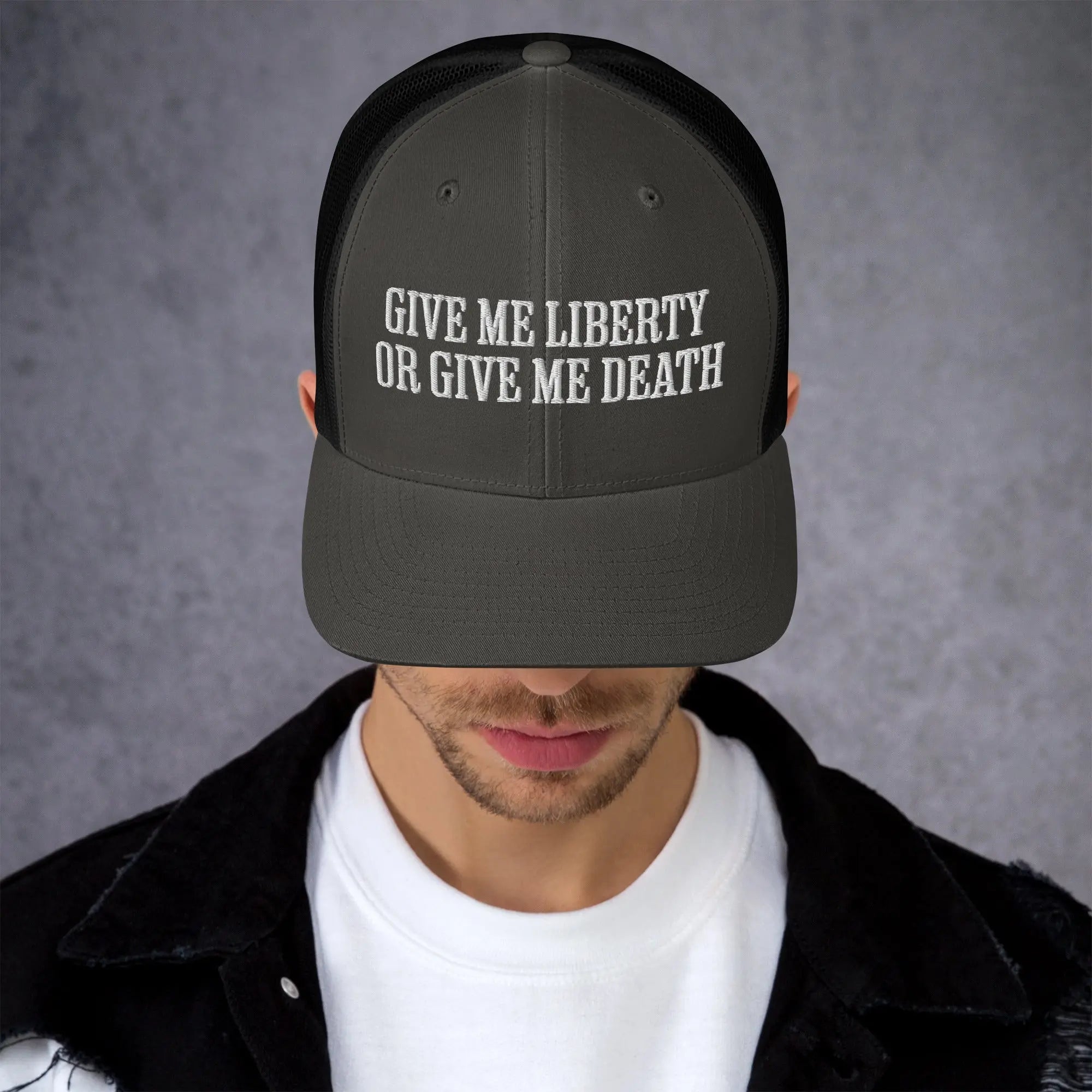 A man wearing a charcoal and black patriotic trucker hat with the text "Give Me Liberty Or Give Me Death."