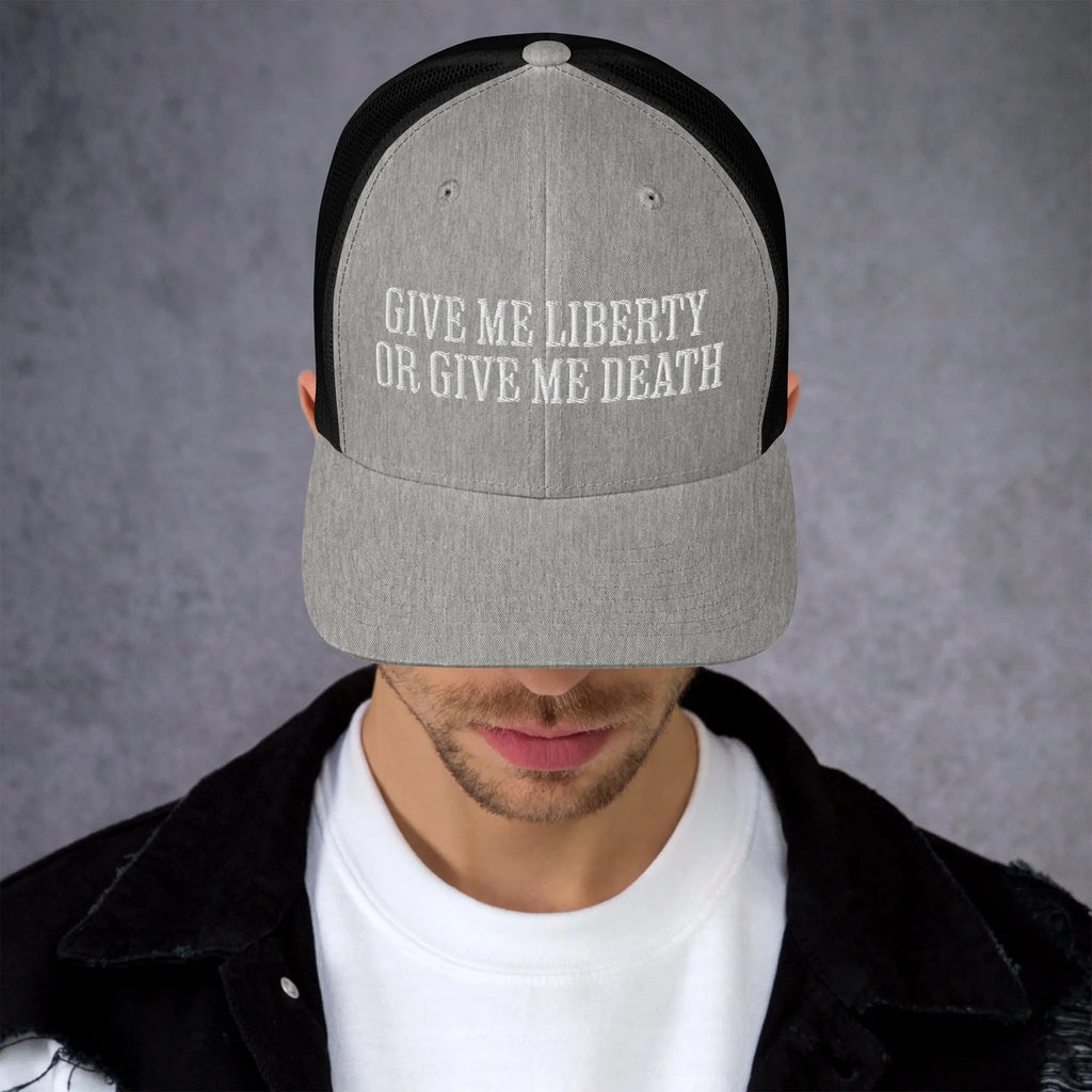 A man wearing a black and light grey patriotic trucker hat with the text "Give Me Liberty Or Give Me Death."