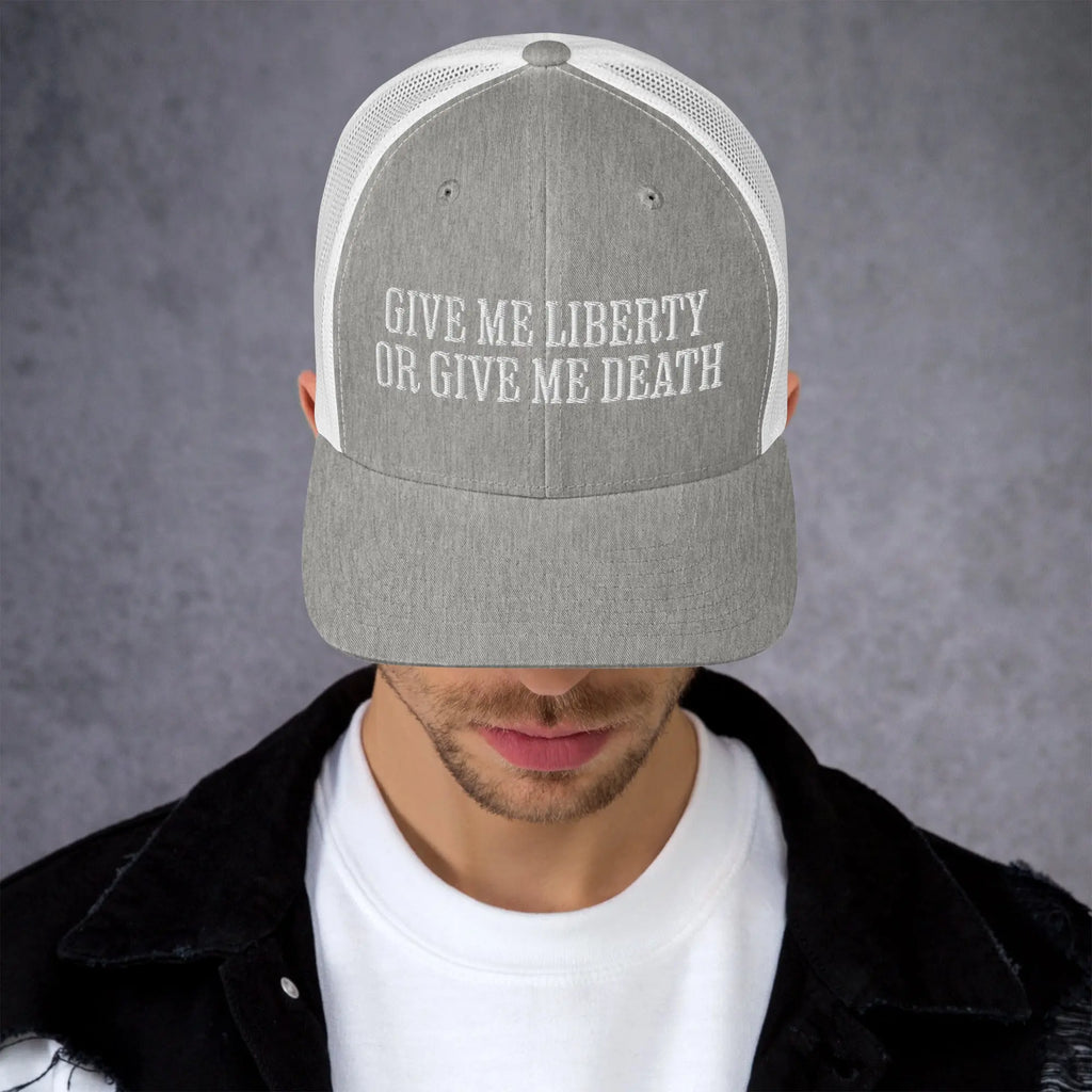 A man wearing a heather grey amd white patriotic trucker hat with the text "Give Me Liberty Or Give Me Death."