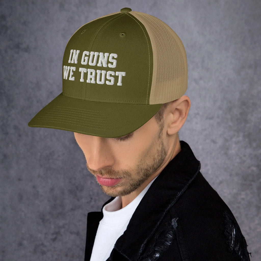 Man wearing a green cap with 'IN GUNS WE TRUST' text on a gray background