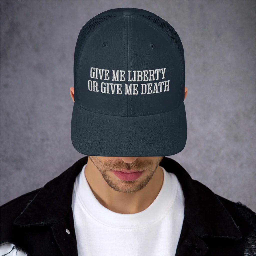 A man wearing a navy patriotic trucker hat with the text "Give Me Liberty Or Give Me Death."