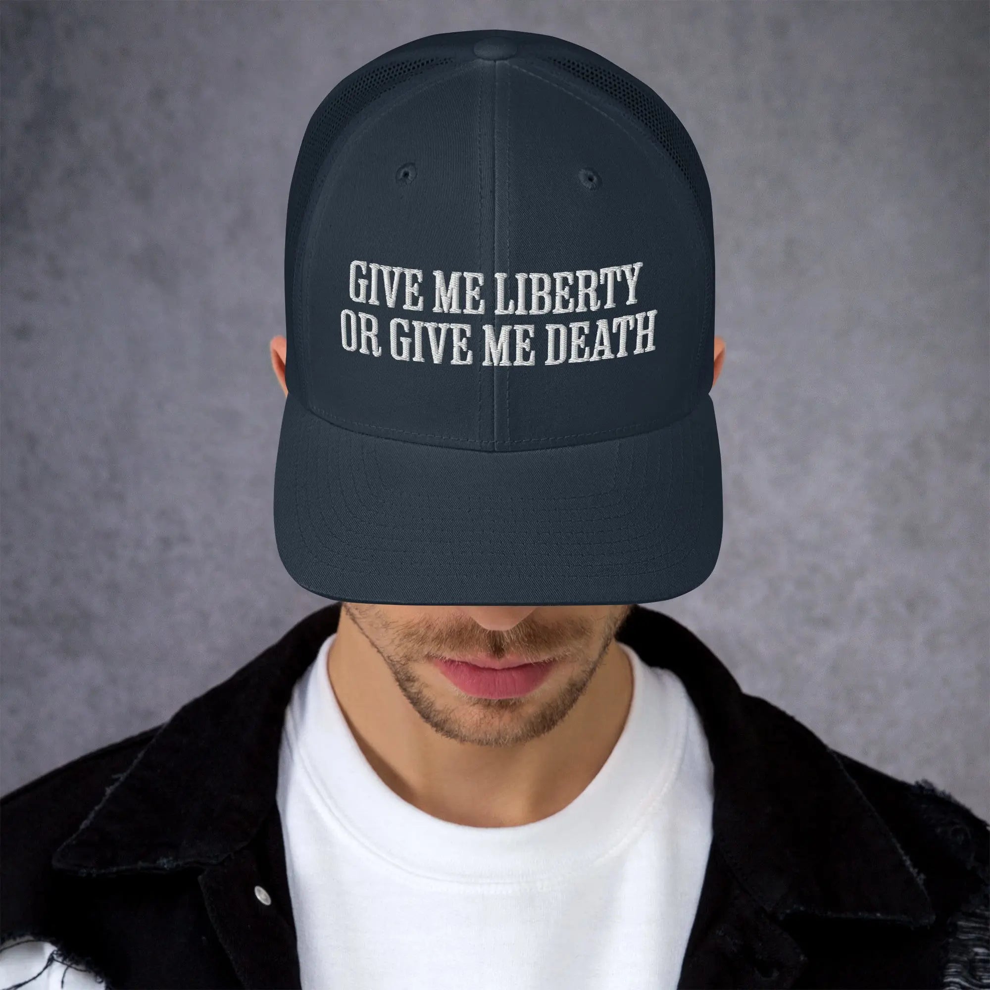 A man wearing a navy patriotic trucker hat with the text "Give Me Liberty Or Give Me Death."