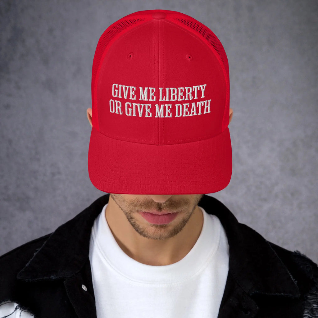 A man wearing a red patriotic trucker hat with the text "Give Me Liberty Or Give Me Death."