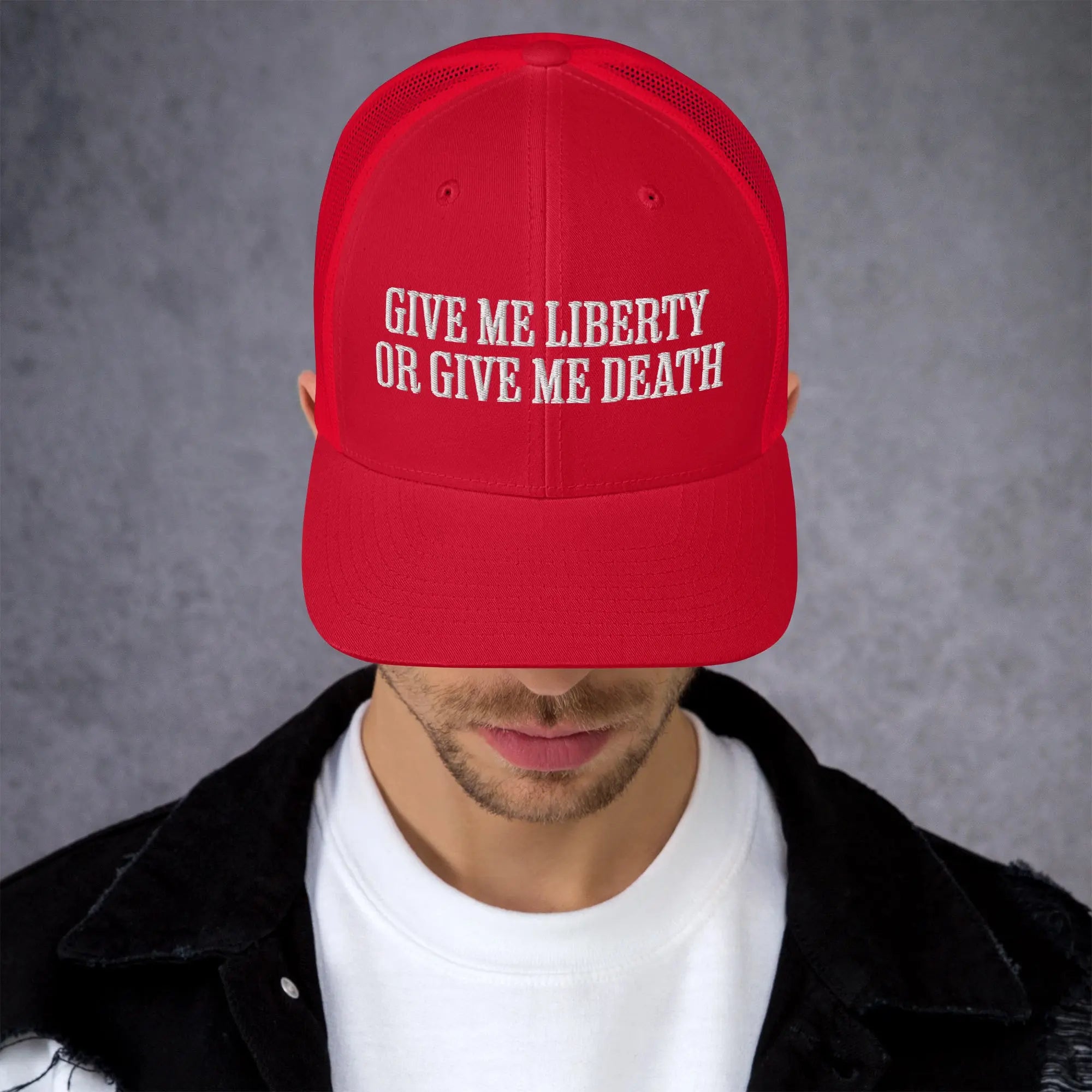 A man wearing a red patriotic trucker hat with the text "Give Me Liberty Or Give Me Death."