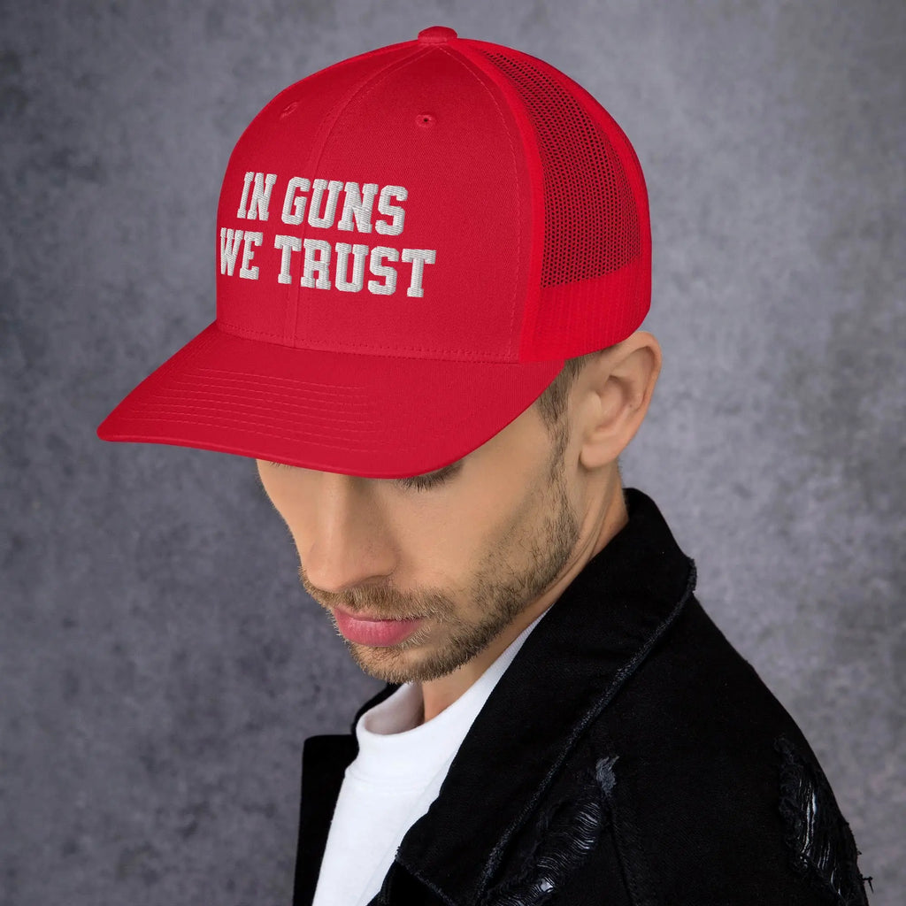 Man wearing a red cap with 'IN GUNS WE TRUST' text on a gray background