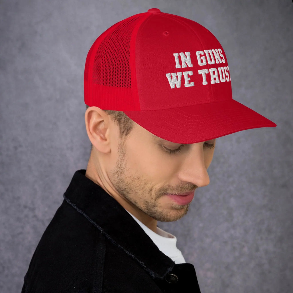Man wearing a red cap with 'IN GUNS WE TRUST' text on a gray background