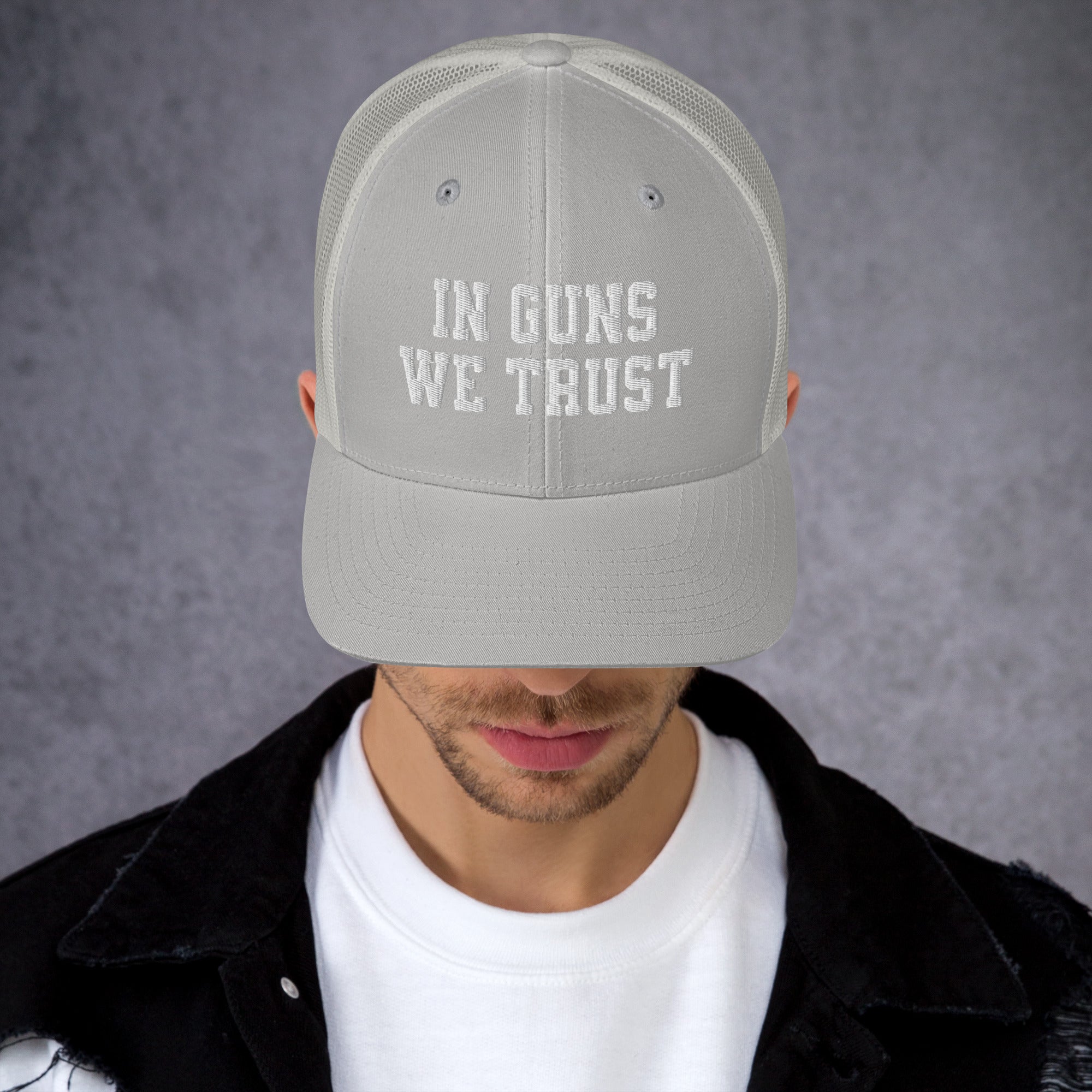 Person wearing a gray cap with 'IN GUNS WE TRUST' text on a gray background