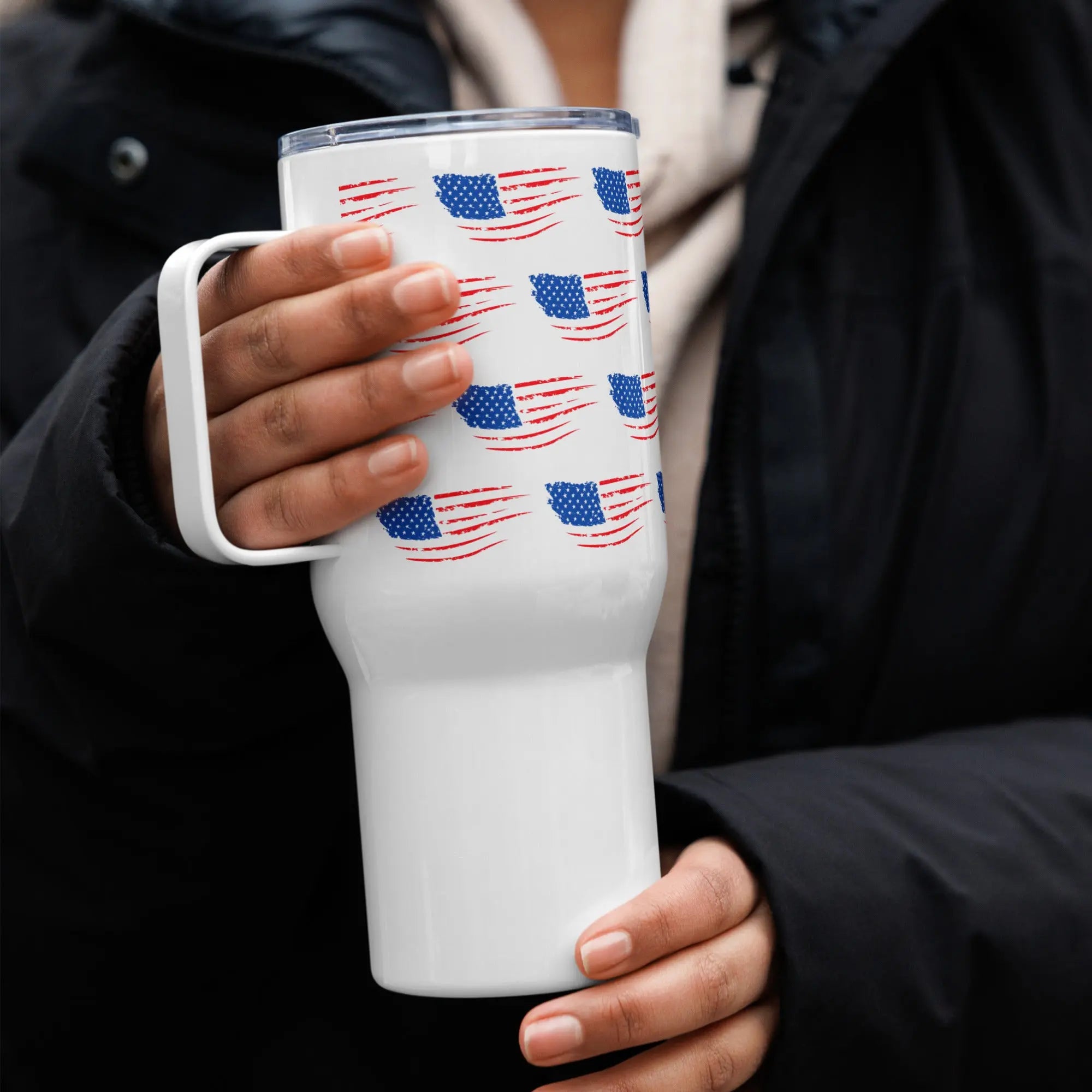 White tumbler with American flag pattern held by a person wearing a black coat.