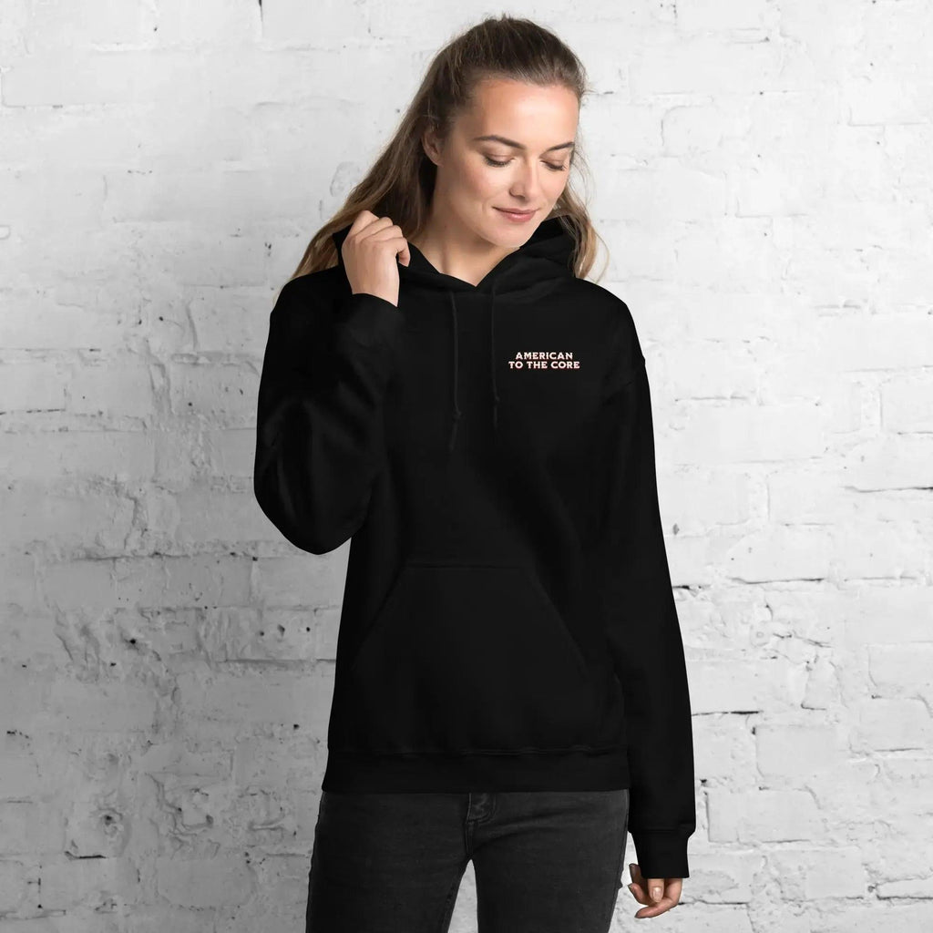 A woman wearing a black patriotic hoodie with the text "American to the core."