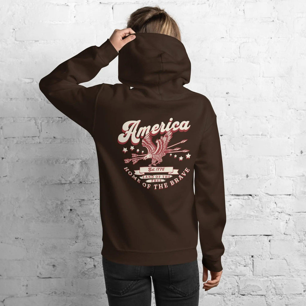 Back of a woman wearing a dark chocolate patriotic hoodie with an eagle and the text "America home of the brave."