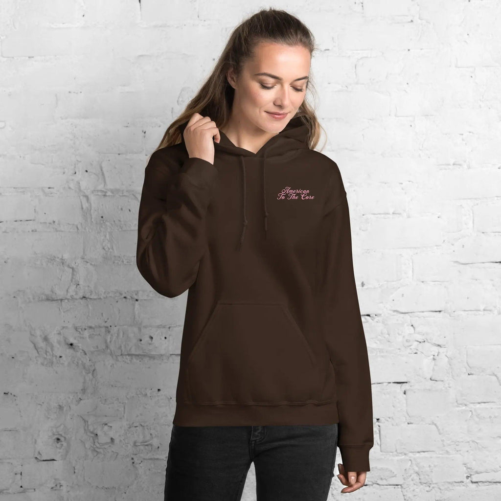 A woman wearing a dark chocolate patriotic hoodie with the text "American To The Core"