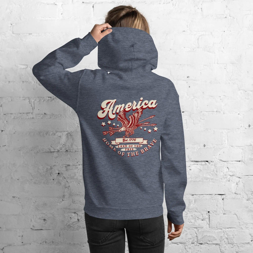 Back of a woman wearing a heather patriotic hoodie with an eagle and the text "America home of the brave."