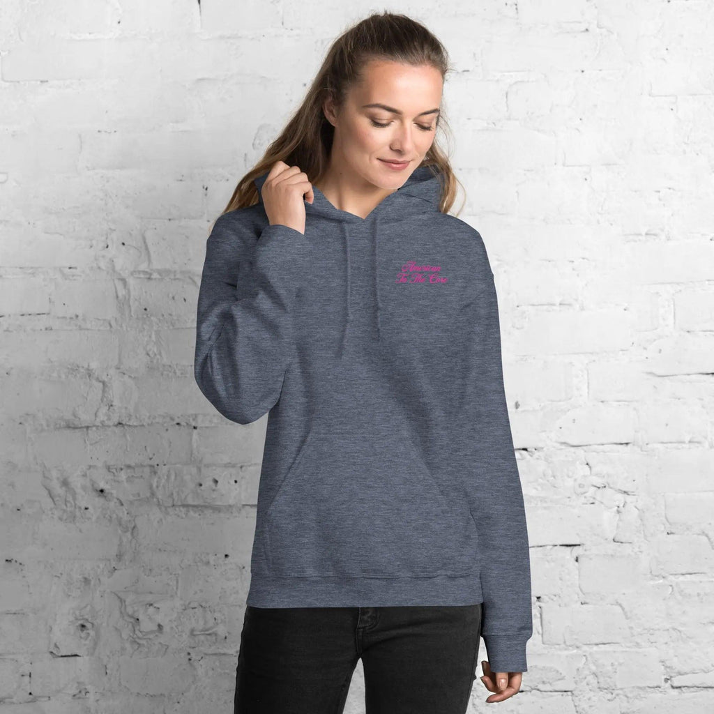 A woman wearing a patriotic heather sport hoodie with the text "American To The Core" in pink.