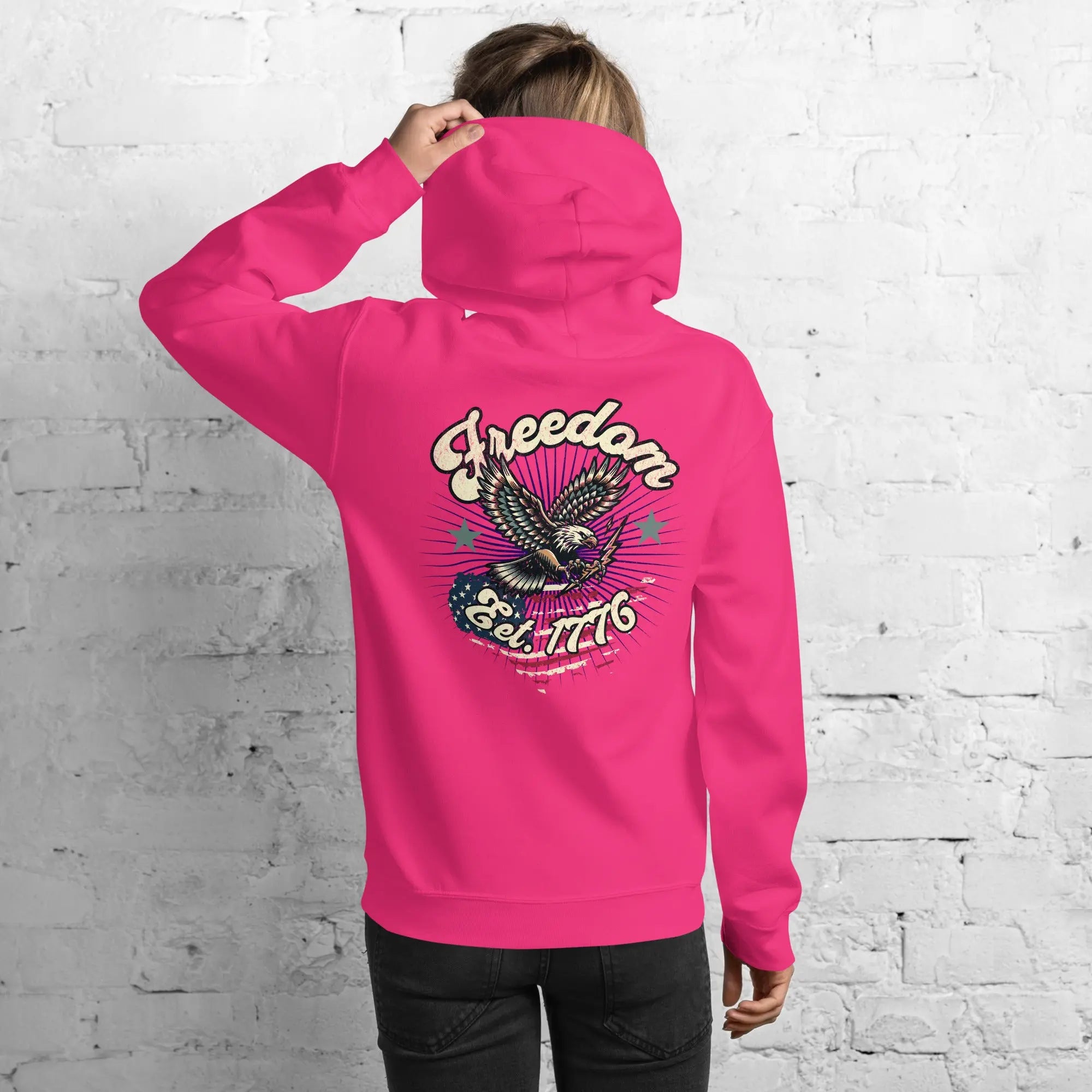 Back of woman wearing a heliconia-colored patriotic hoodie with an eagle and the text "Freedom Est. 1776" 