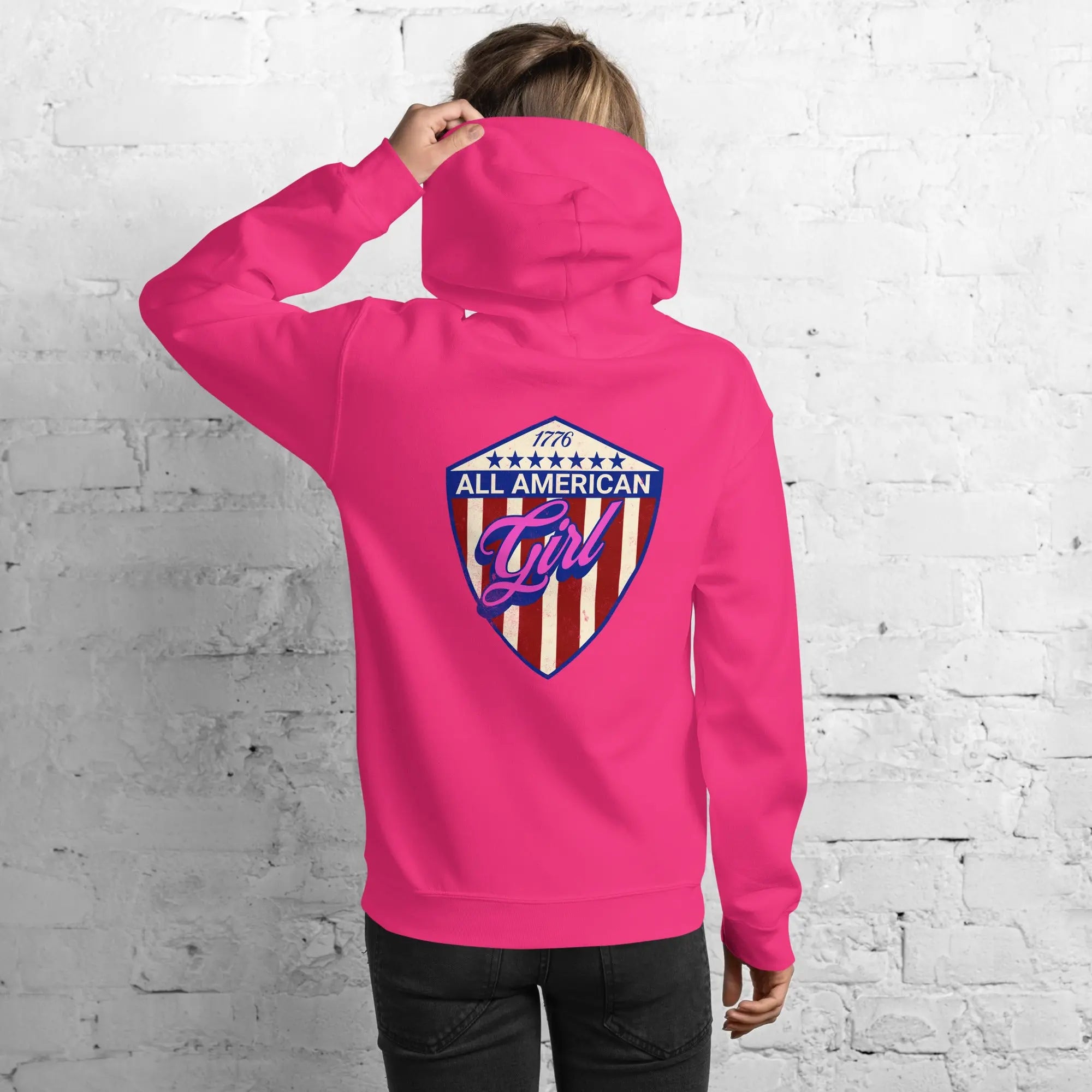 Back of a woman wearing a patriotic heliconia hoodie with the text "All American Girl" over a patriotic design. 