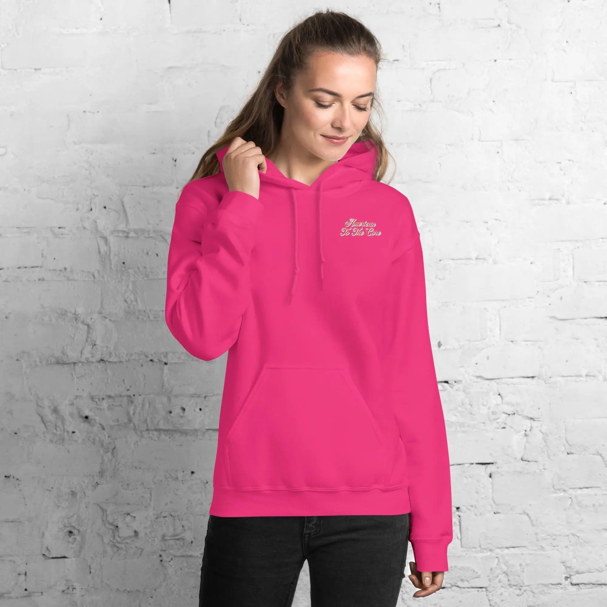 A woman wearing a heliconia, patriotic hoodie with the text "American to the core."