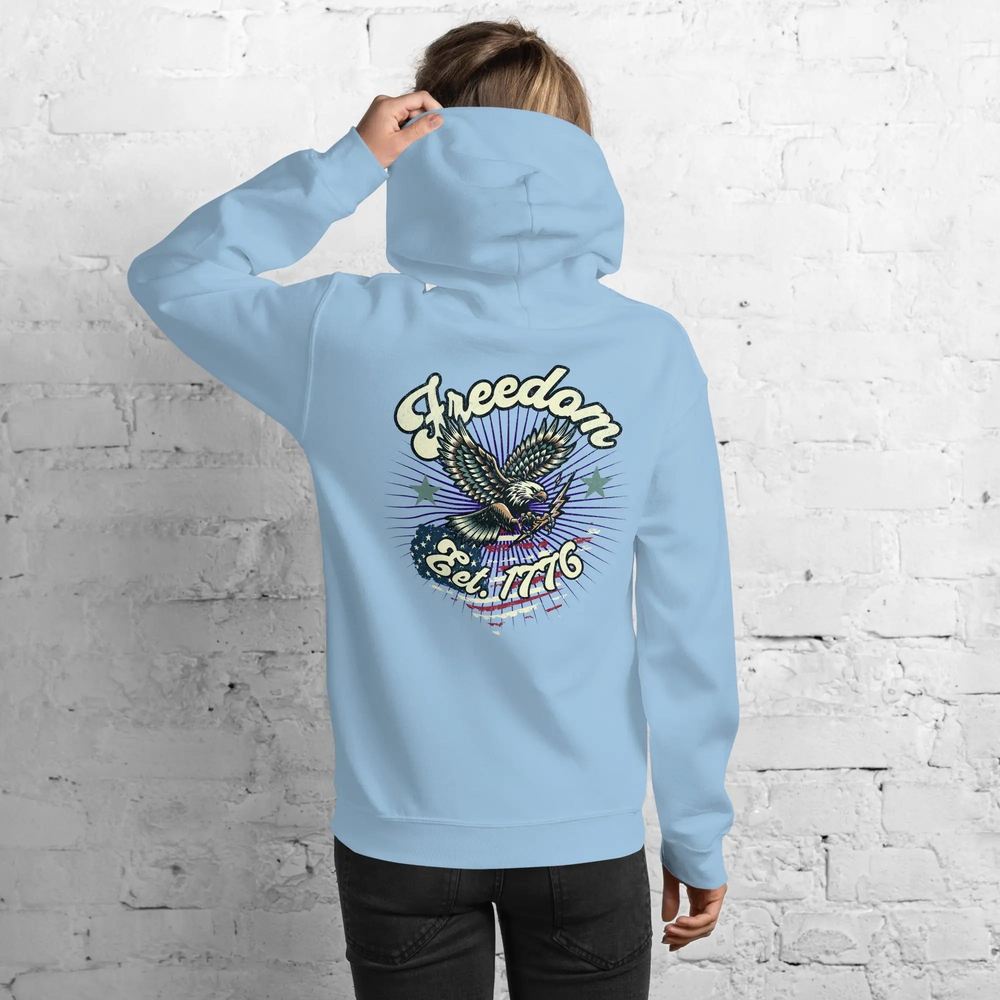 Back of woman wearing a light blue patriotic hoodie with an eagle and the text "Freedom Est. 1776" 