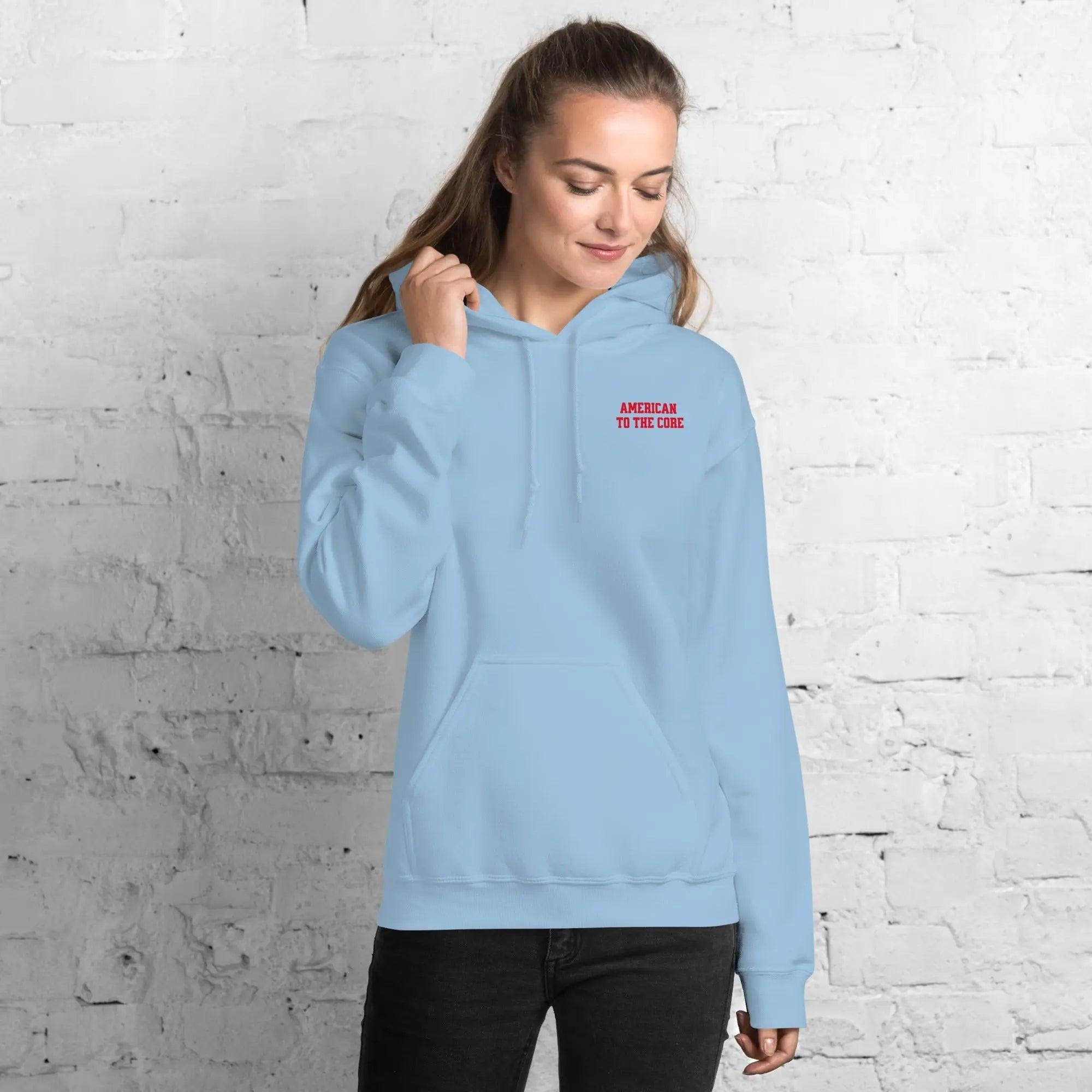 A woman wearing a light blue hoodie with the text "American to the core"