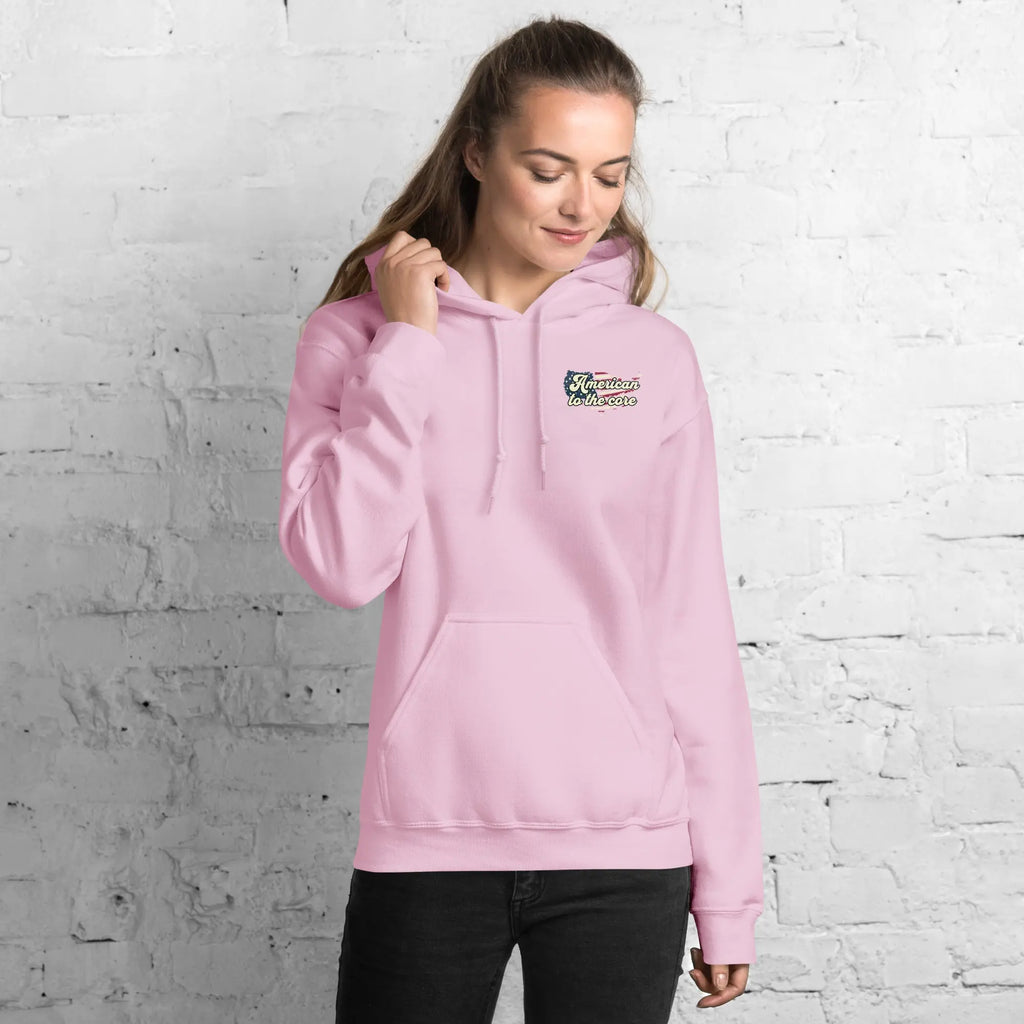 Woman wearing a light pink patriotic hoodie with the text "American to the core" 