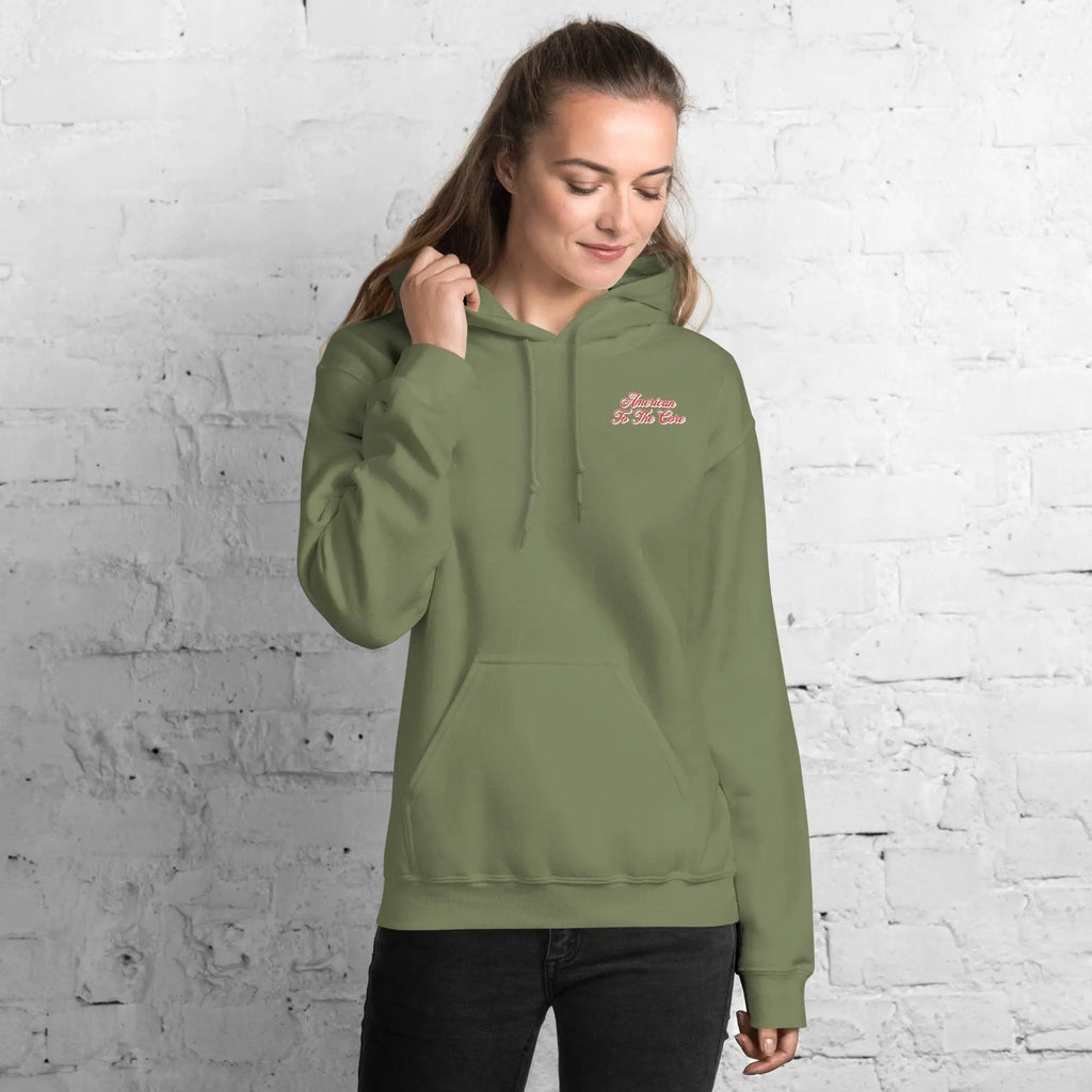 A woman wearing a military green, patriotic hoodie with the text "American to the core."