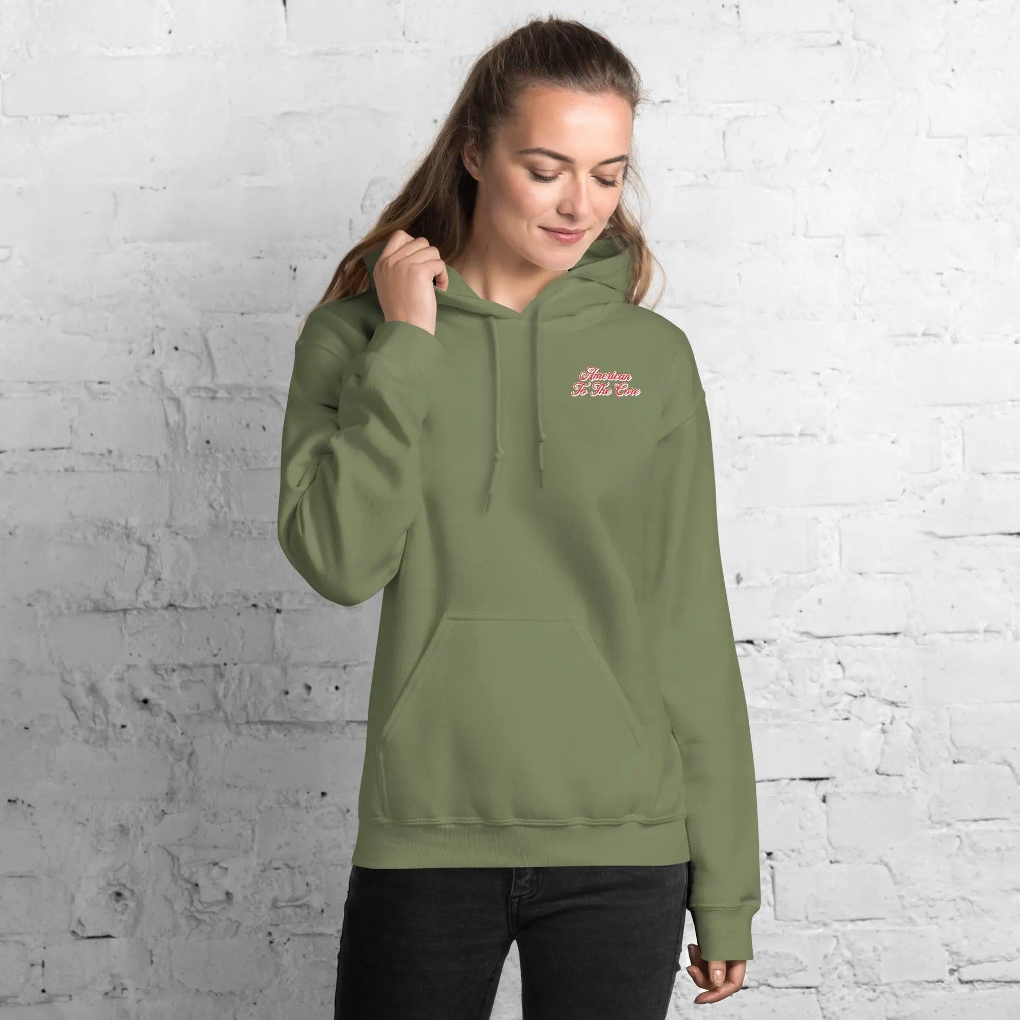 A woman wearing a military green, patriotic hoodie with the text "American to the core."