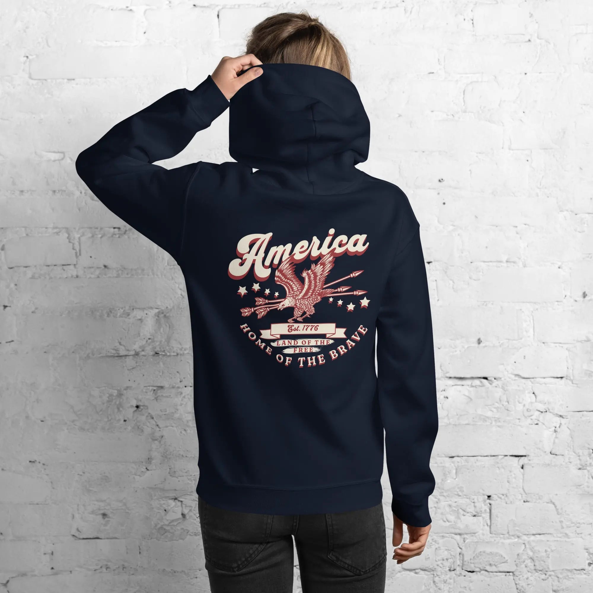 Back of a woman wearing a navy patriotic hoodie with an eagle and the text "America home of the brave."