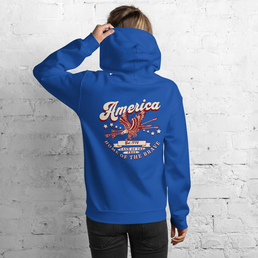 Back of a woman wearing a royal blue patriotic hoodie with an eagle and the text "America home of the brave."