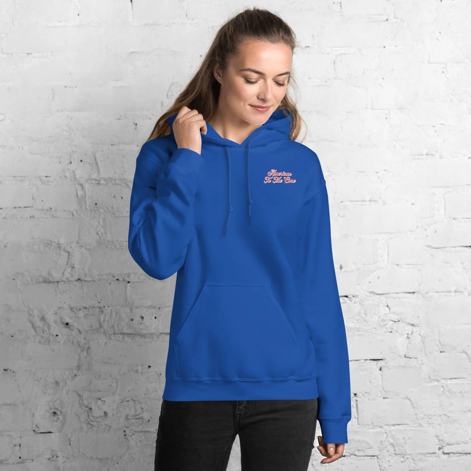 A woman wearing a royal blue, patriotic hoodie with the text "American to the core."