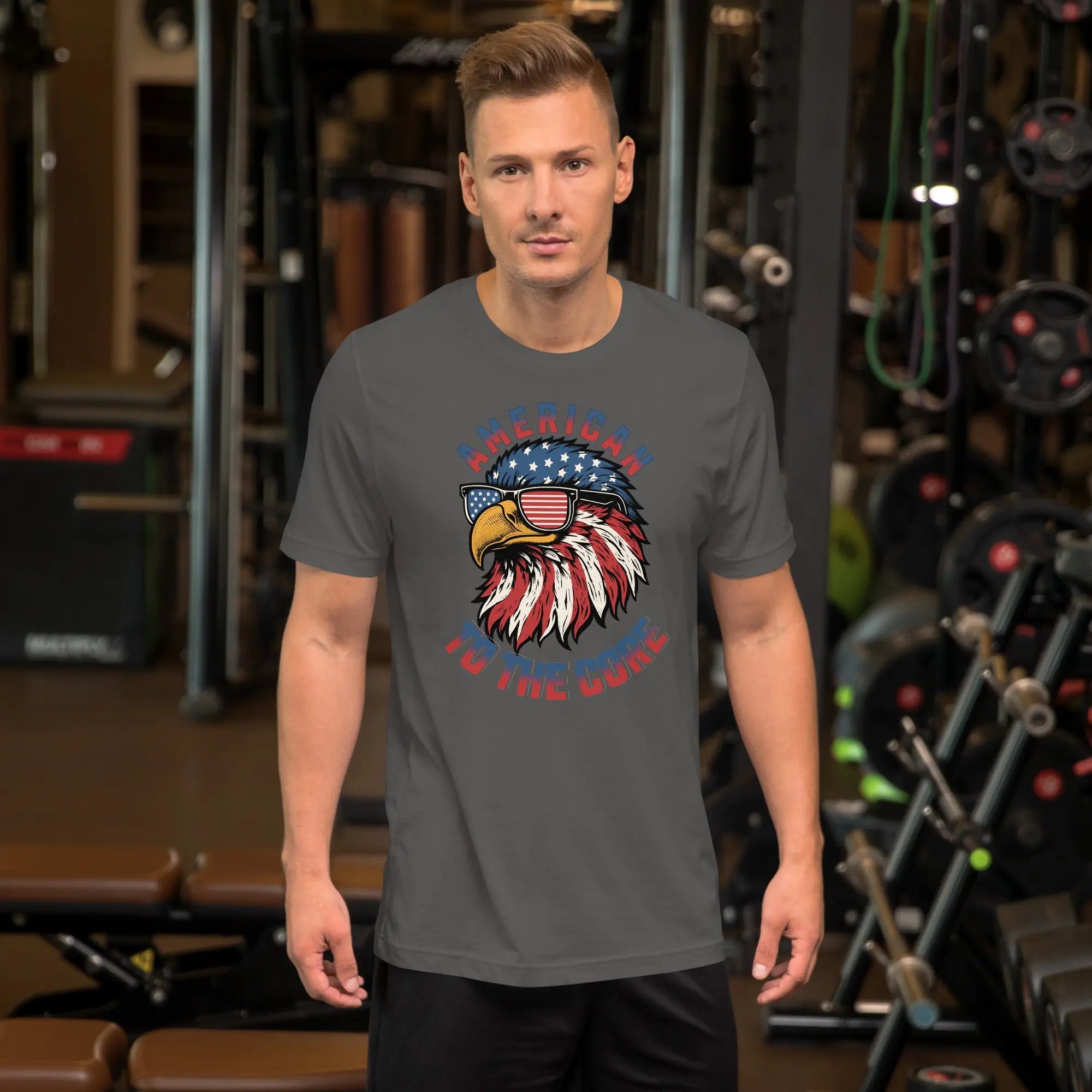 A man wearing a gray patriotic t-shirt with an eagle head with "American to the core" text.