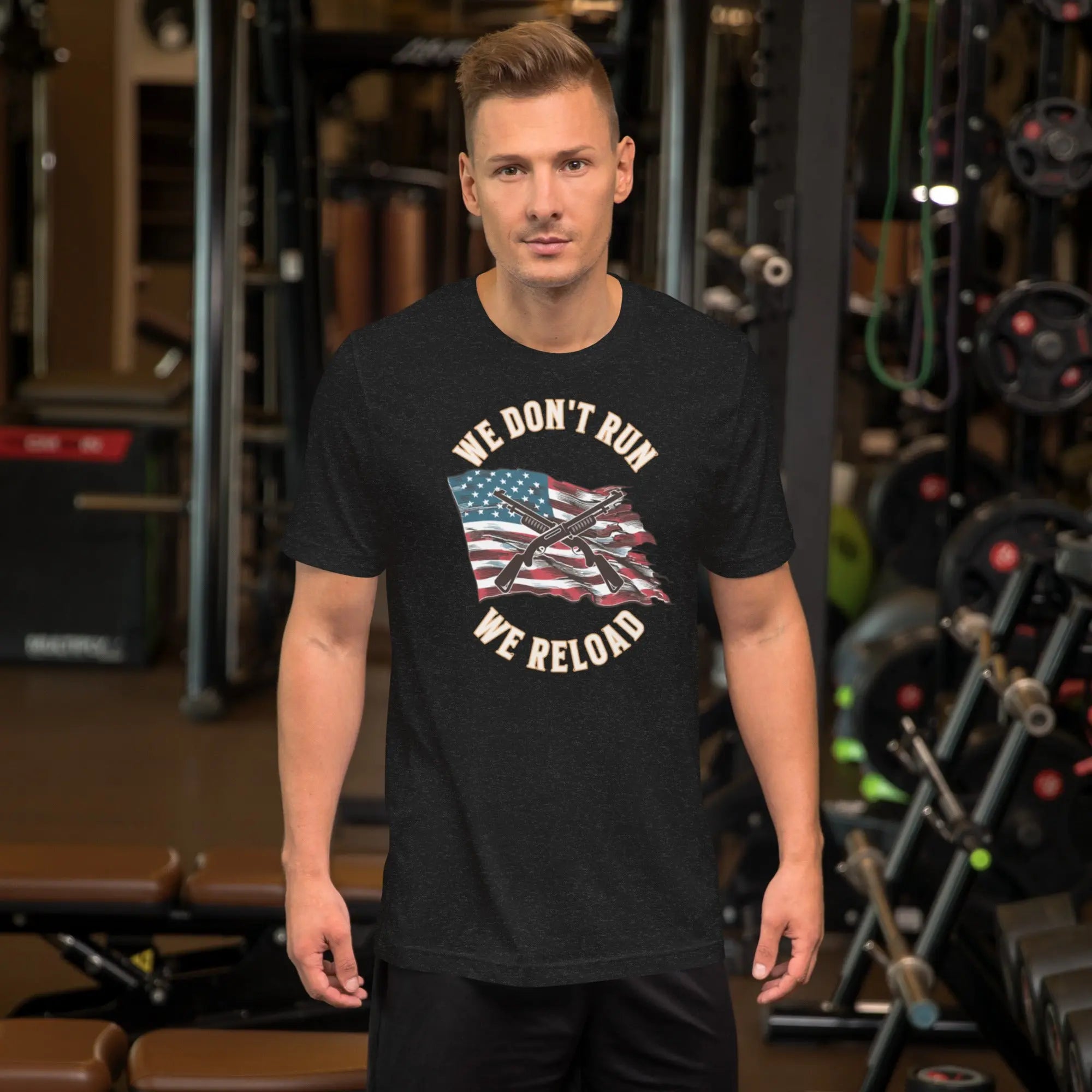 A man wearing a black heather patriotic t-shirt with shotguns over the American flag and the "We don't run, we reload" text.