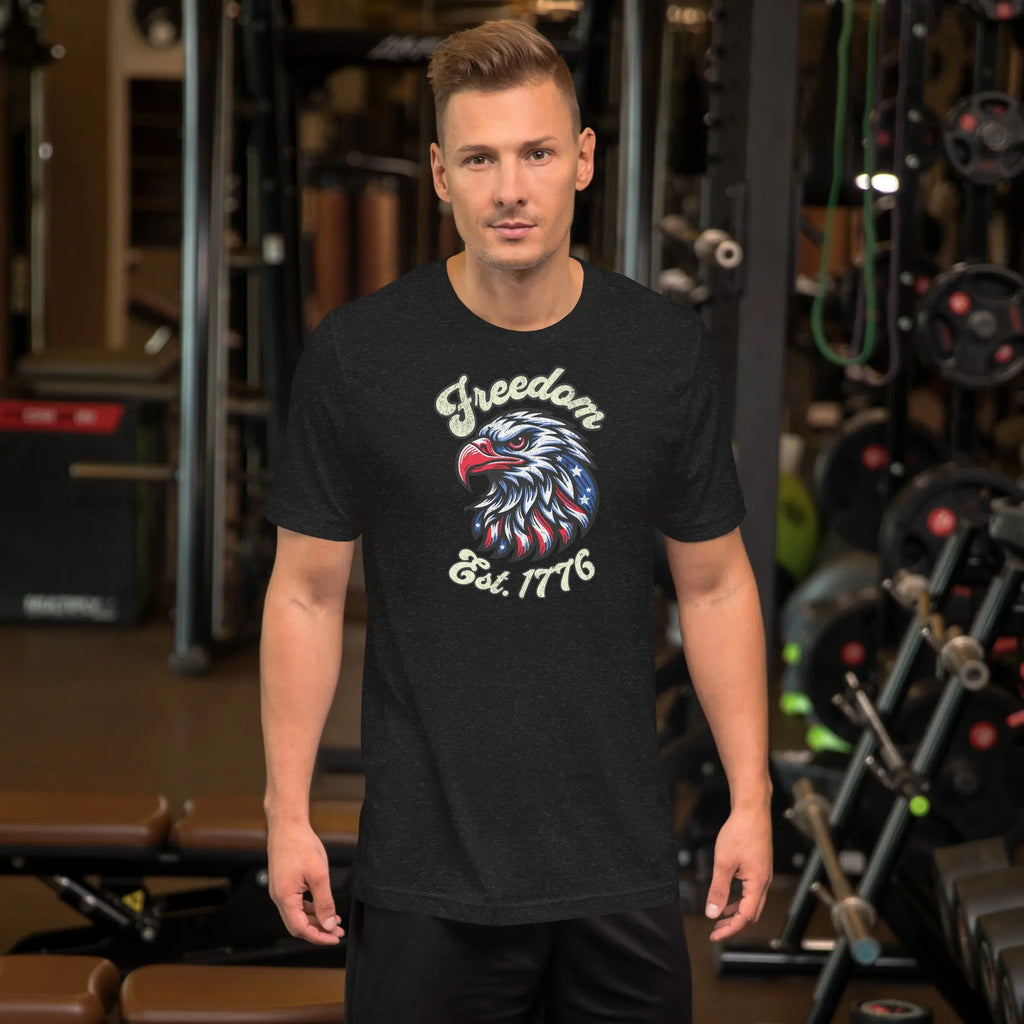 A man wearing a black heather patriotic t-shirt with an eagle head with "Freedom Est. 1776" text.