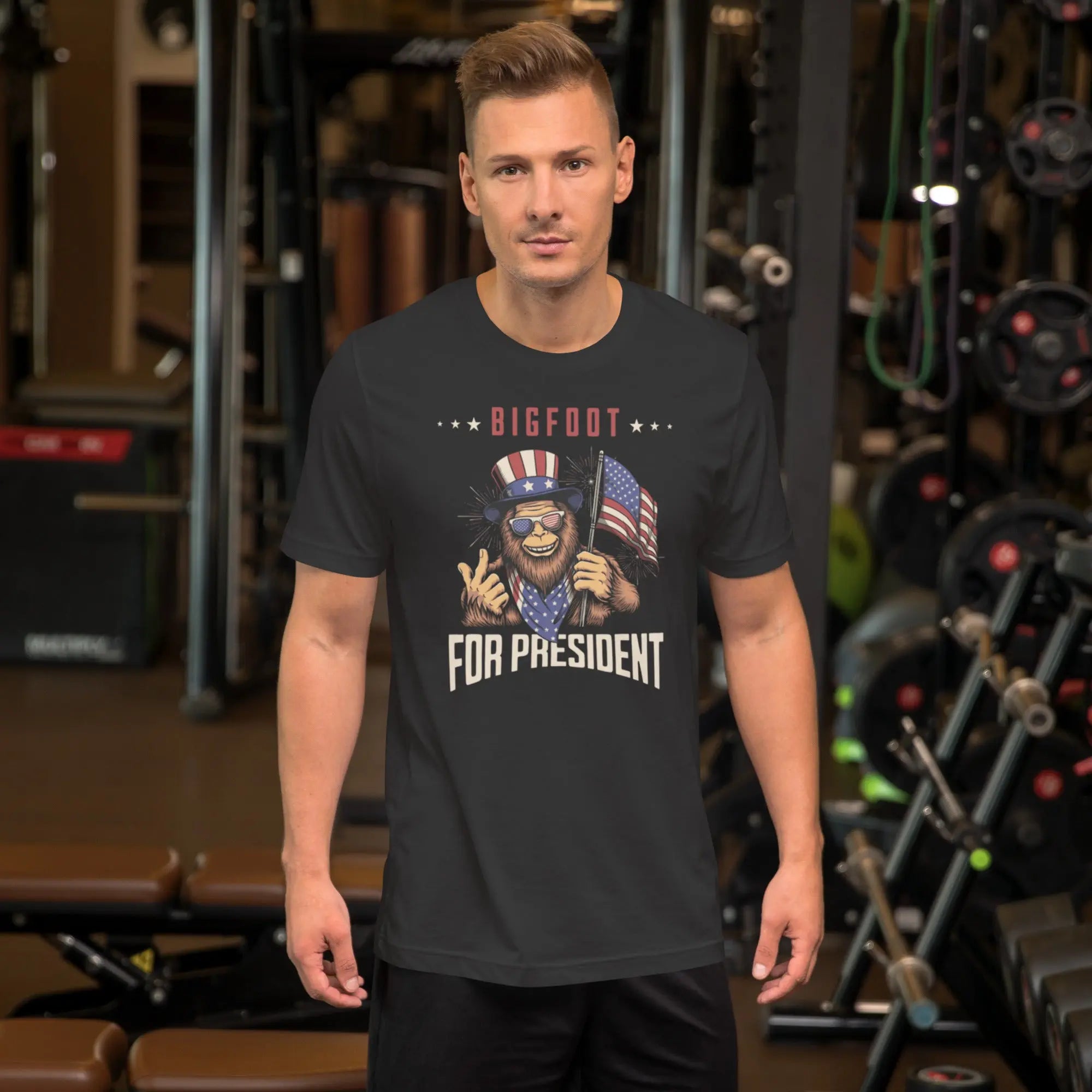 man wearing a dark grey patriotic t-shirt with a image of bigfoot with "Bigfoot for president" text
