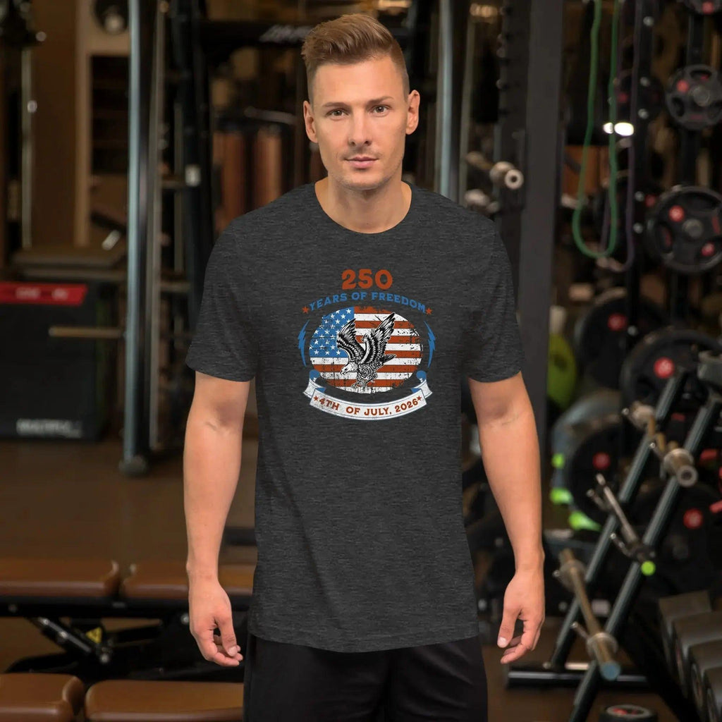 A man wearing a dark grey heather patriotic men's t-shirt with an eagle over the American flag and the text "250 years of freedom, 4th of July, 2026."