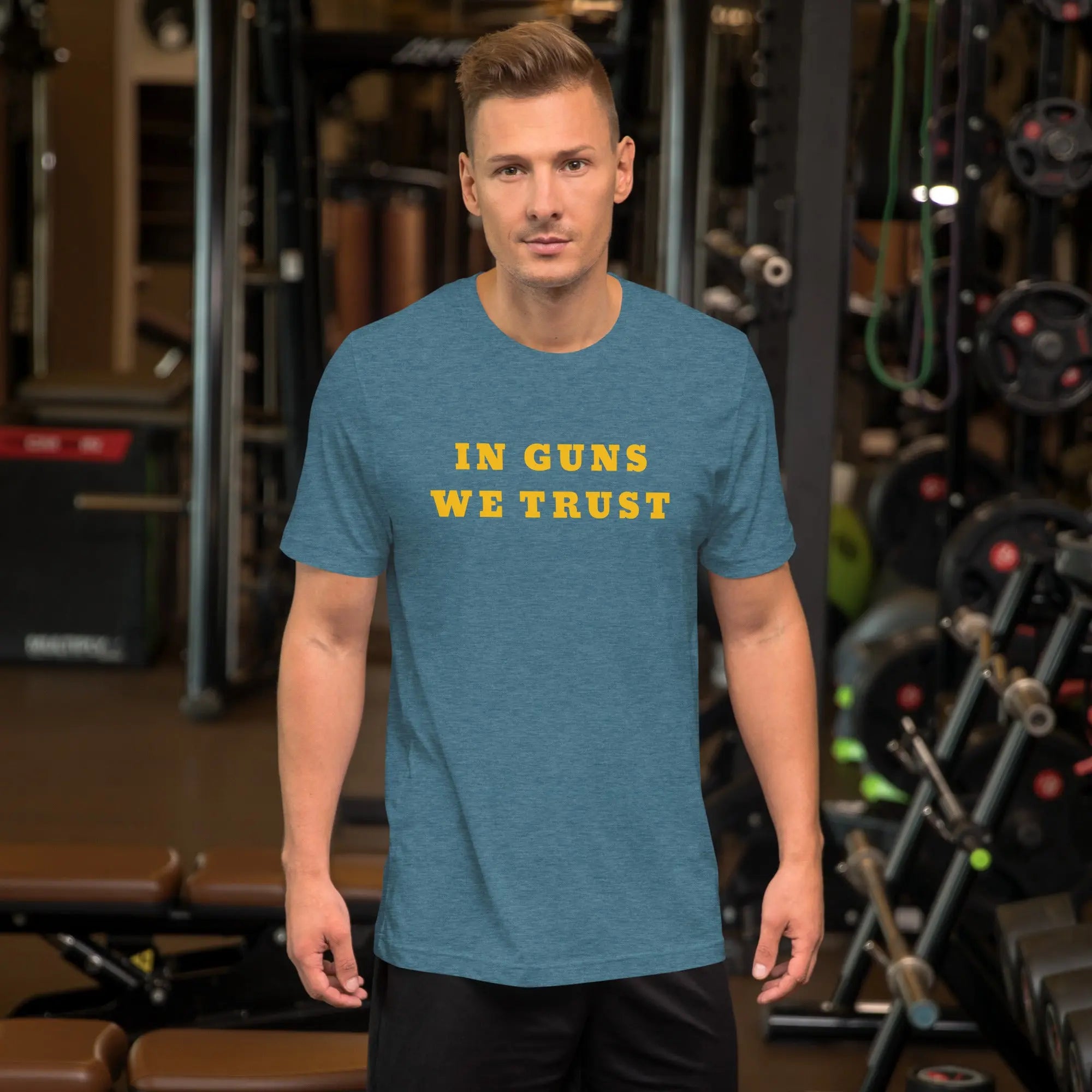 A man wearing a heather deep teal patriotic t-shirt with yellow "In Guns We Trust" text.