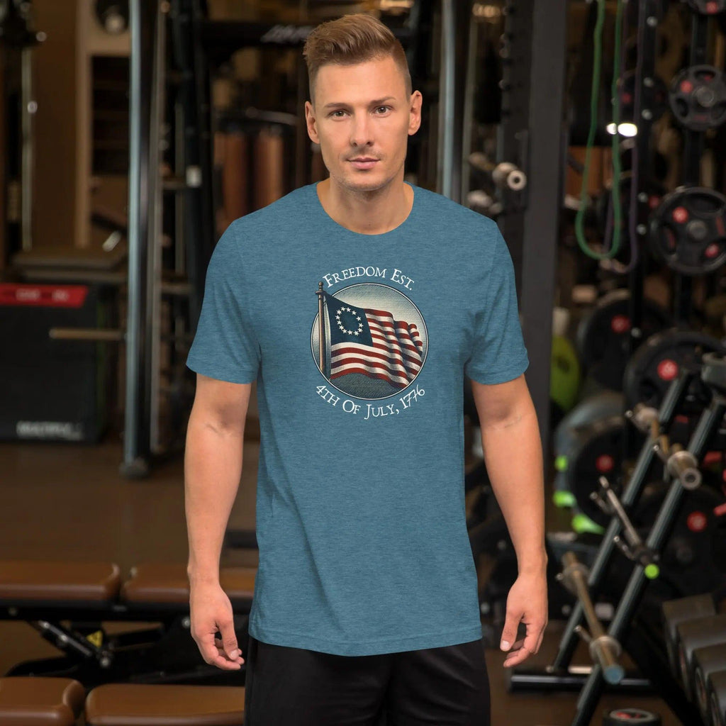 A man wearing a heather deep teal patriotic t-shirt. With the American flag and the text "Freedom est. 4th of July, 1776." 