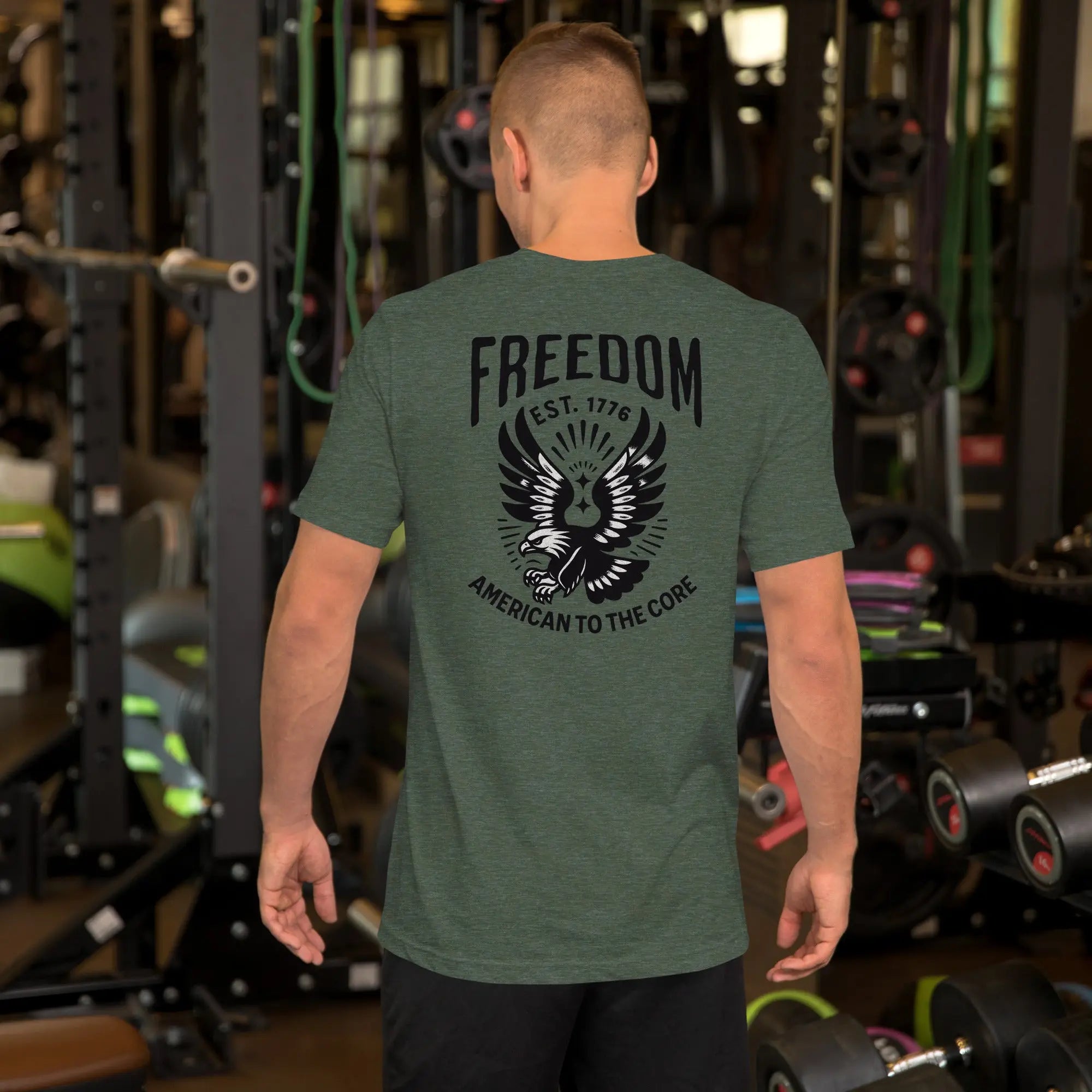Back of man wearing a forest heather patriotic t-shirt with an eagle and "freedom est. 1776" text