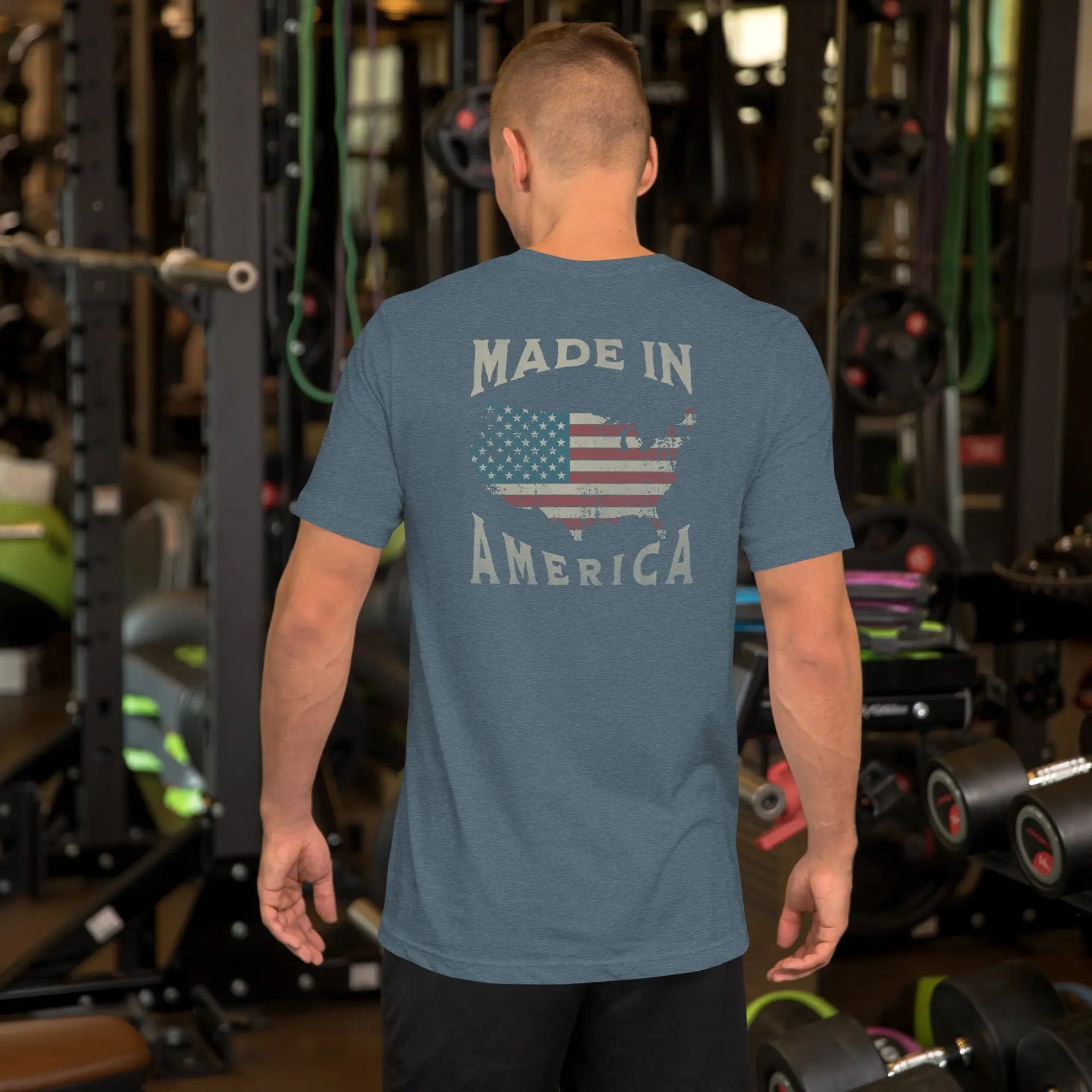 A man wearing a  patriotic t-shirt with "Made in America" text. A silhouette of America with the American flag in it. eather blue