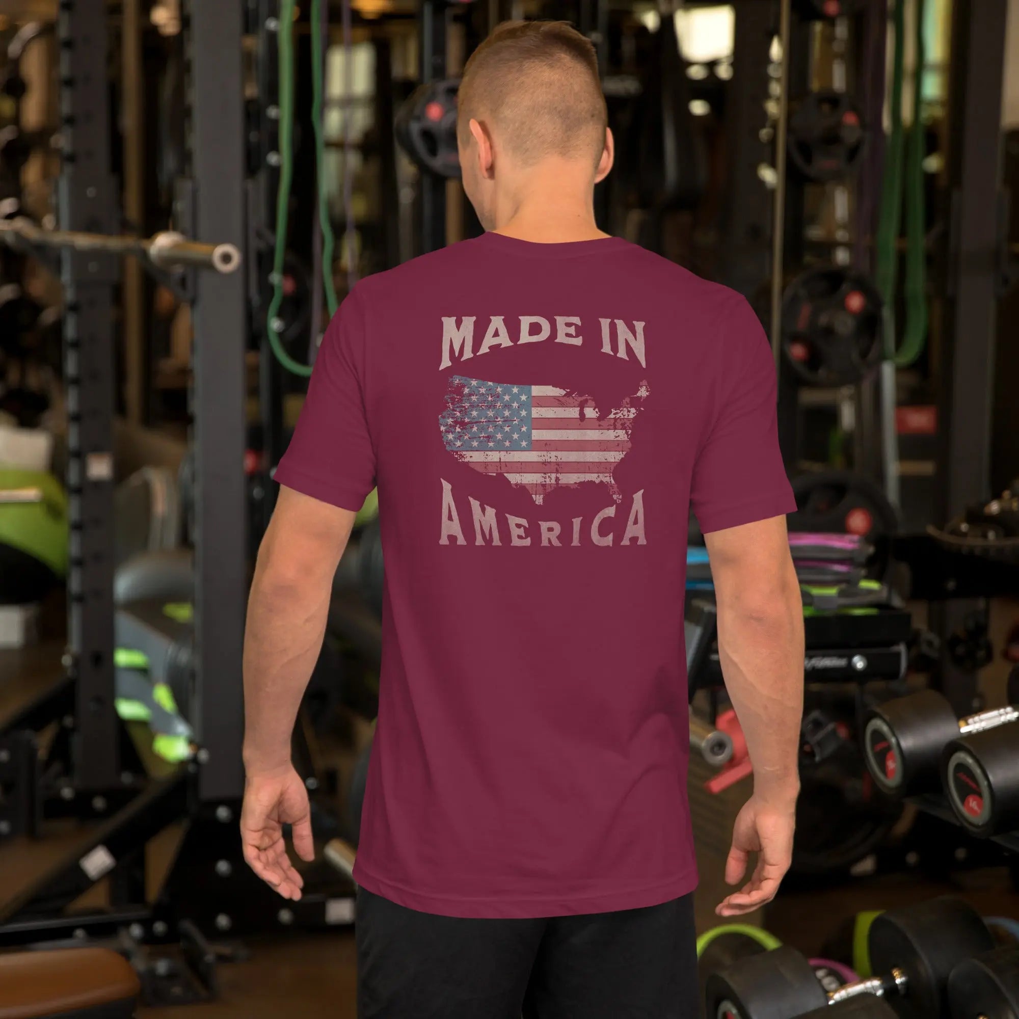 man wearing a maroon patriotic t-shirt with "made in america" text. A silhouette of america with the american flag in it. 