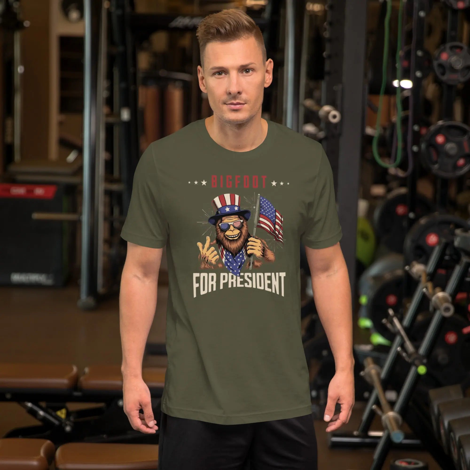 man wearing a heather military green patriotic t-shirt with a image of bigfoot with "Bigfoot for president" text