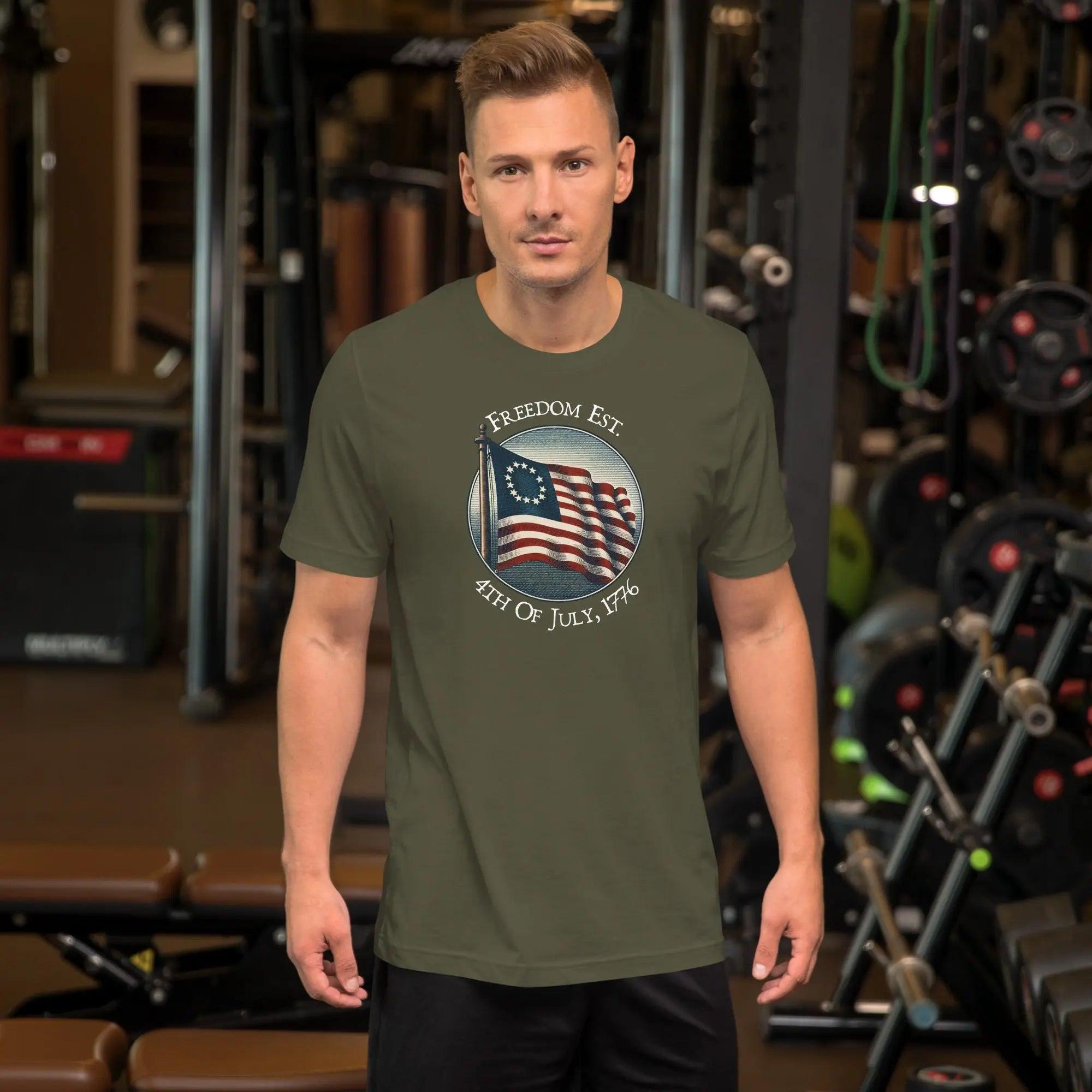 A man wearing a military green patriotic t-shirt. With the American flag and the text "Freedom est. 4th of July, 1776." 