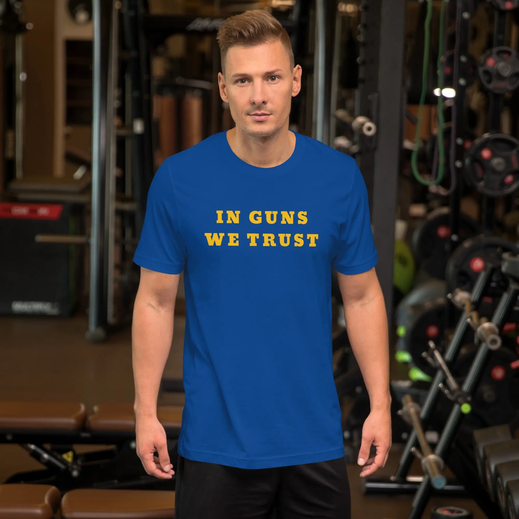 A man wearing a royal blue patriotic t-shirt with yellow "In Guns We Trust" text.