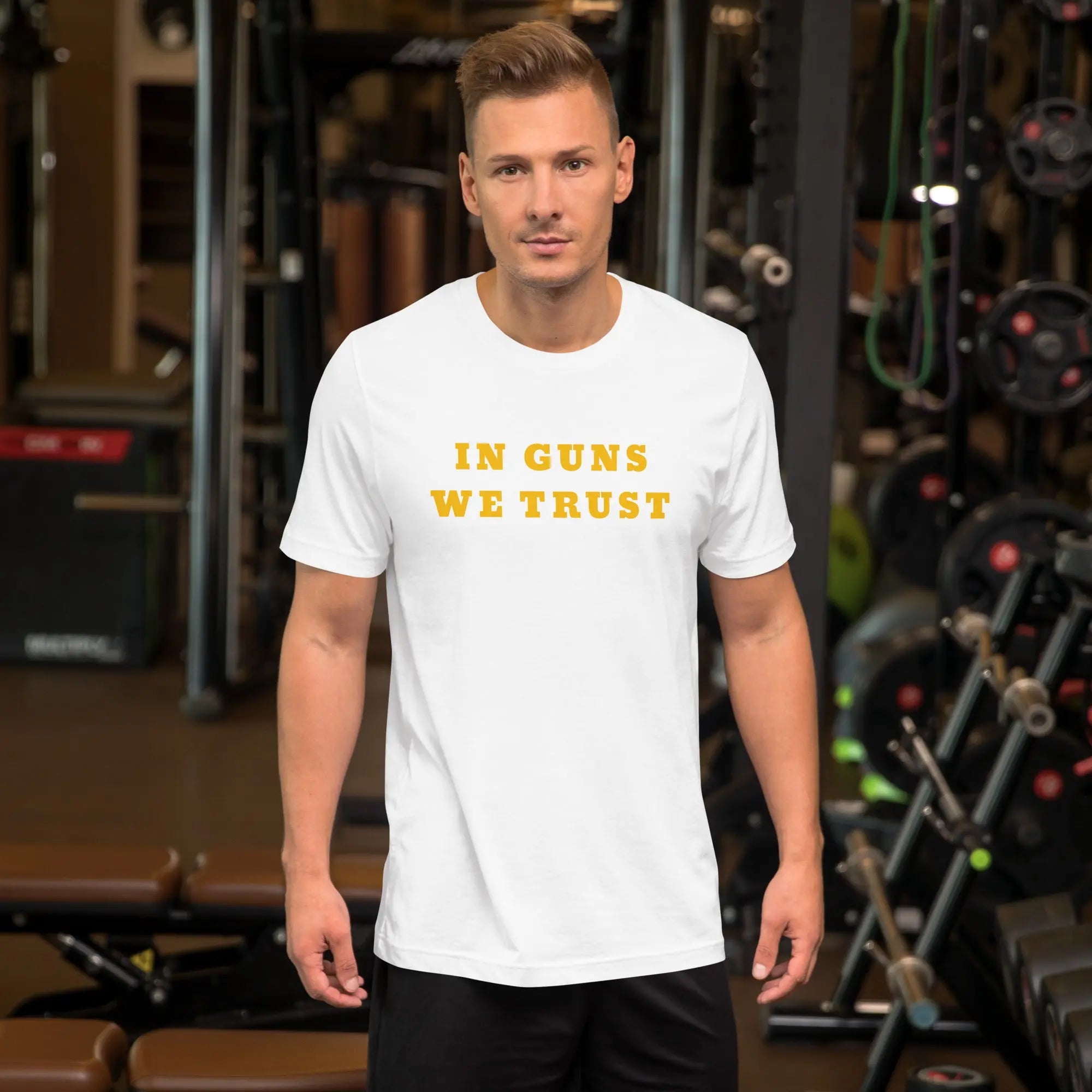 A man wearing a white patriotic t-shirt with yellow "In Guns We Trust" text.