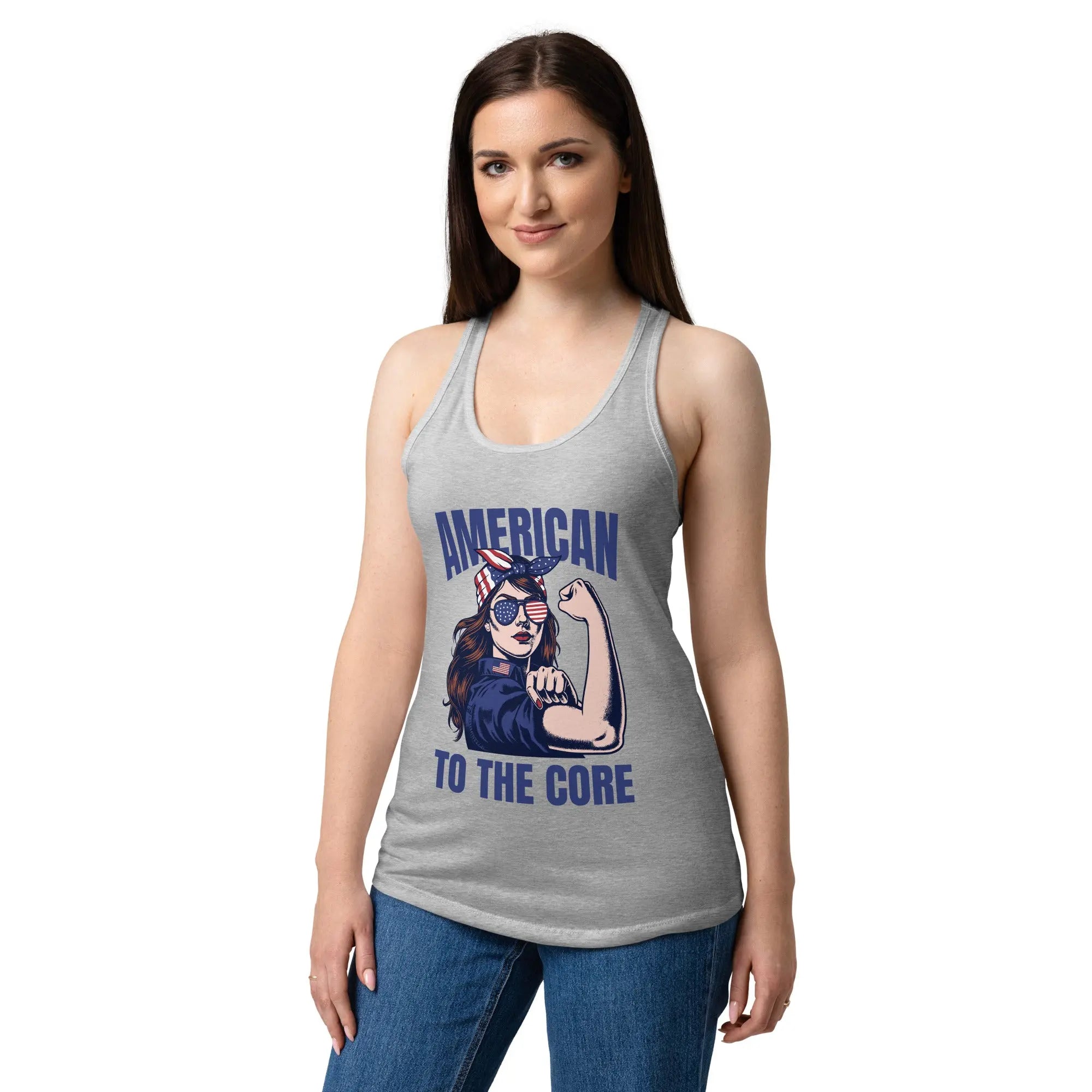 A woman wearing a heather grey, fitted, patriotic racerback tank top with a woman flexing and the text "American to the core."
