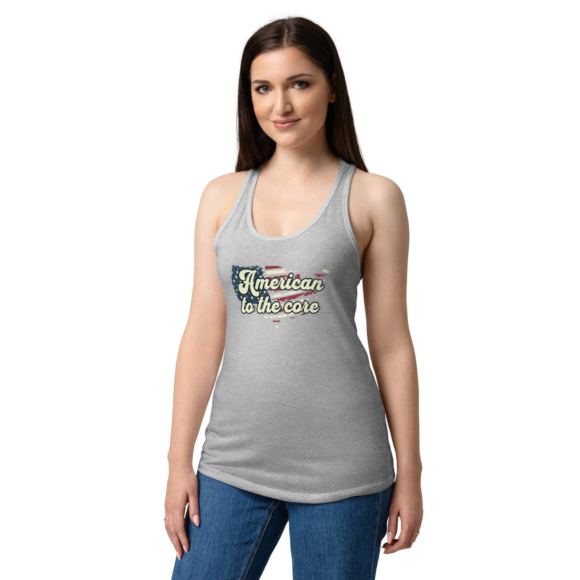 A woman wearing a heather grey, fitted, patriotic racerback tank top with an American flag shaped like the country and the text "American to the core."