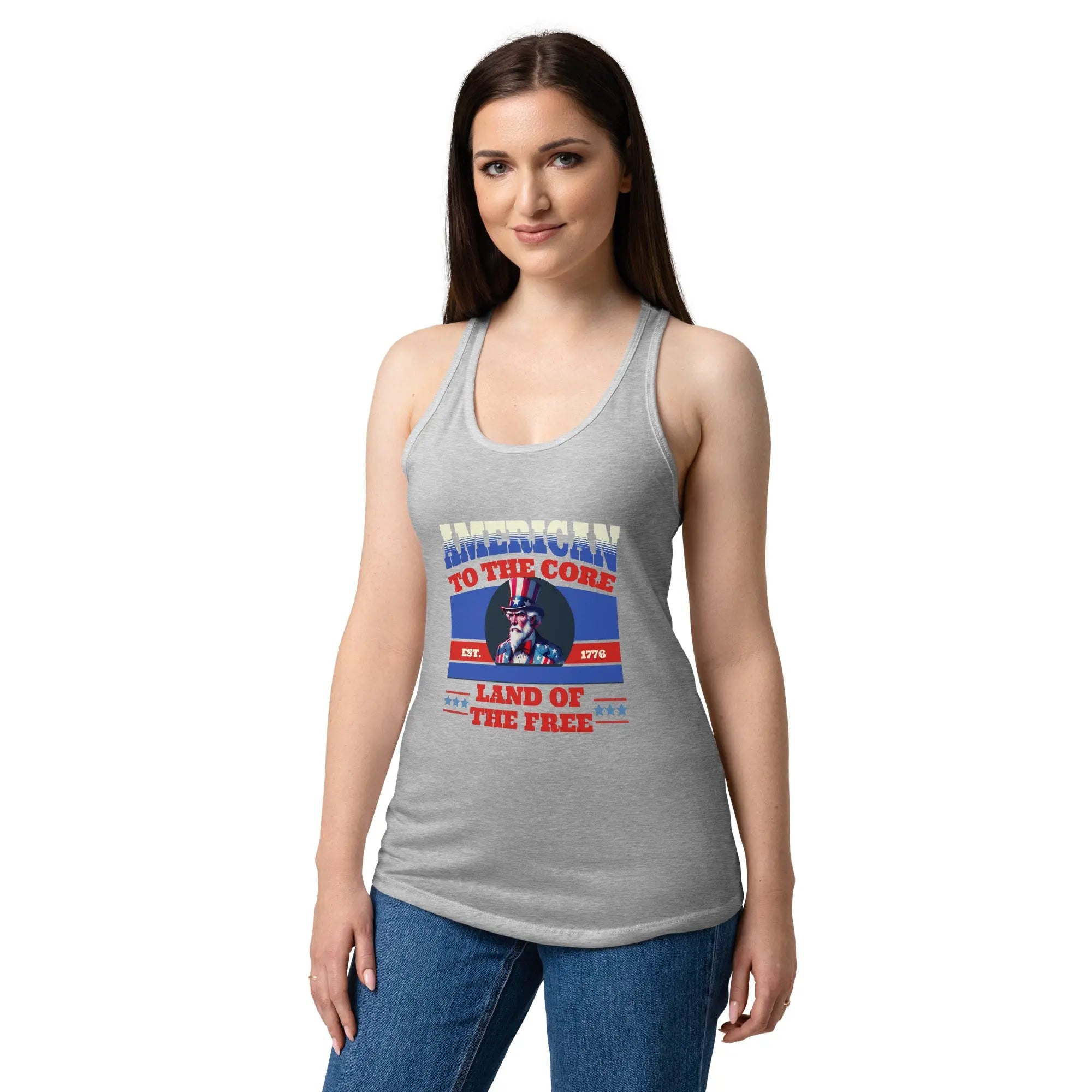 A woman wearing a heather grey patriotic tank top with Uncle Sam and the text "American To The Core" in red, white, and blue. 