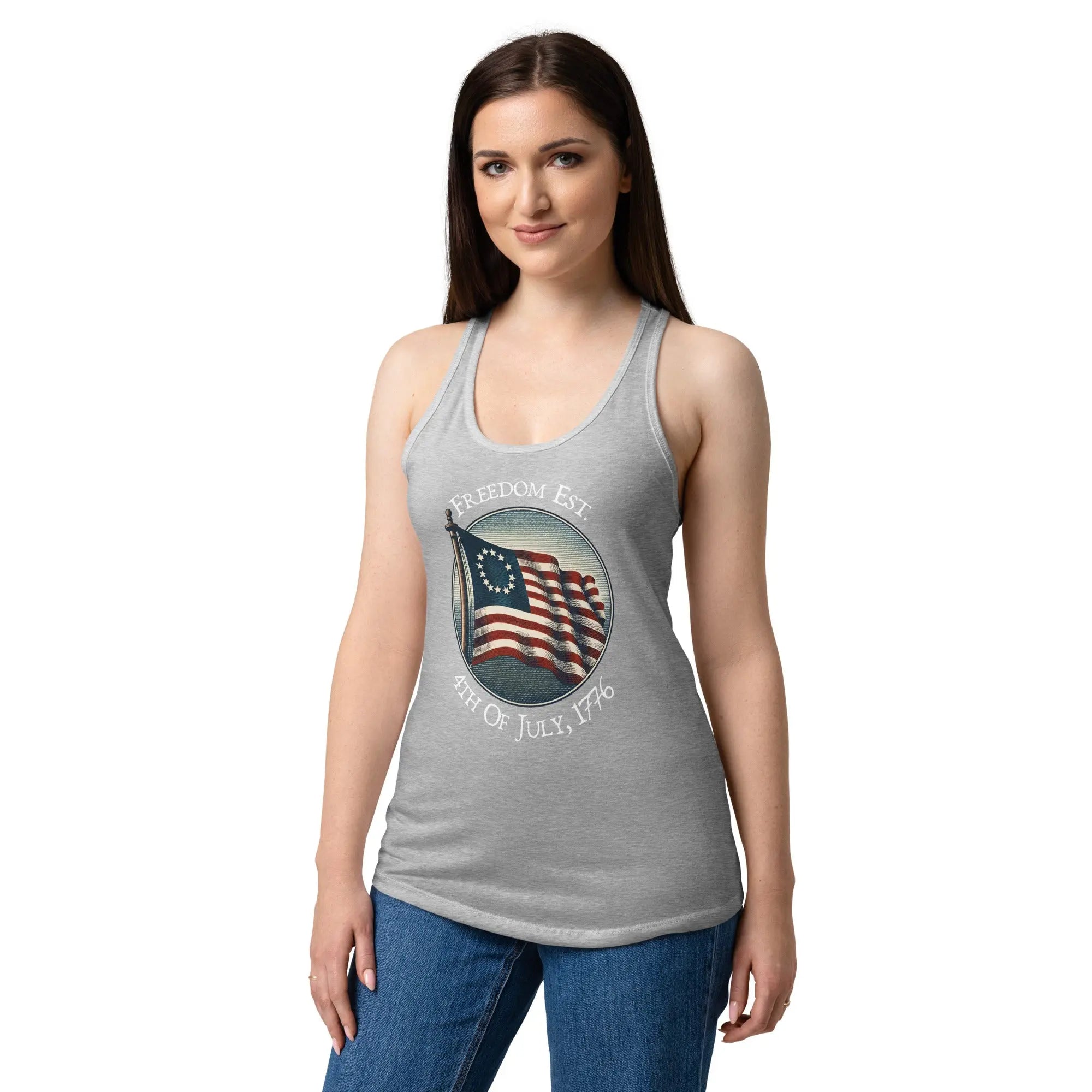 A woman wearing a heather grey patriotic racerback tank top with the American flag and the text "Freedom Est. 4th of July, 1776."