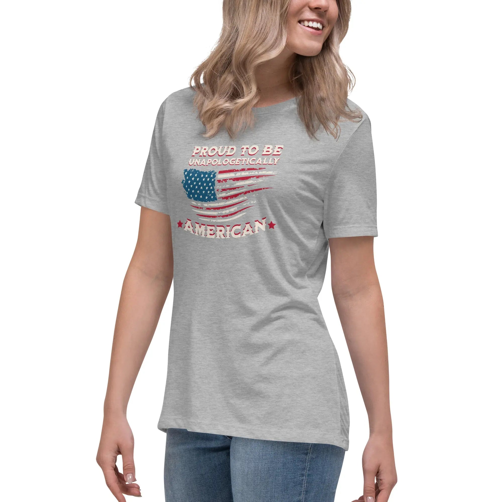 A woman wearing a athletic heather patriotic t-shirt with the American flag and "Proud To Be Unapologetically American" text.